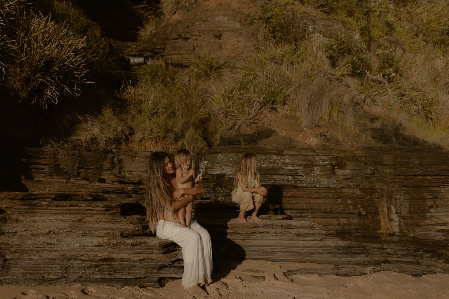 Family enjoying a tender moment against textured rock formations at sunset.