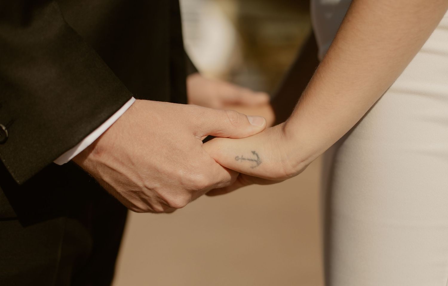 Close-up sequence showing hands with rings and bracelets carefully tearing open brown paper packaging.