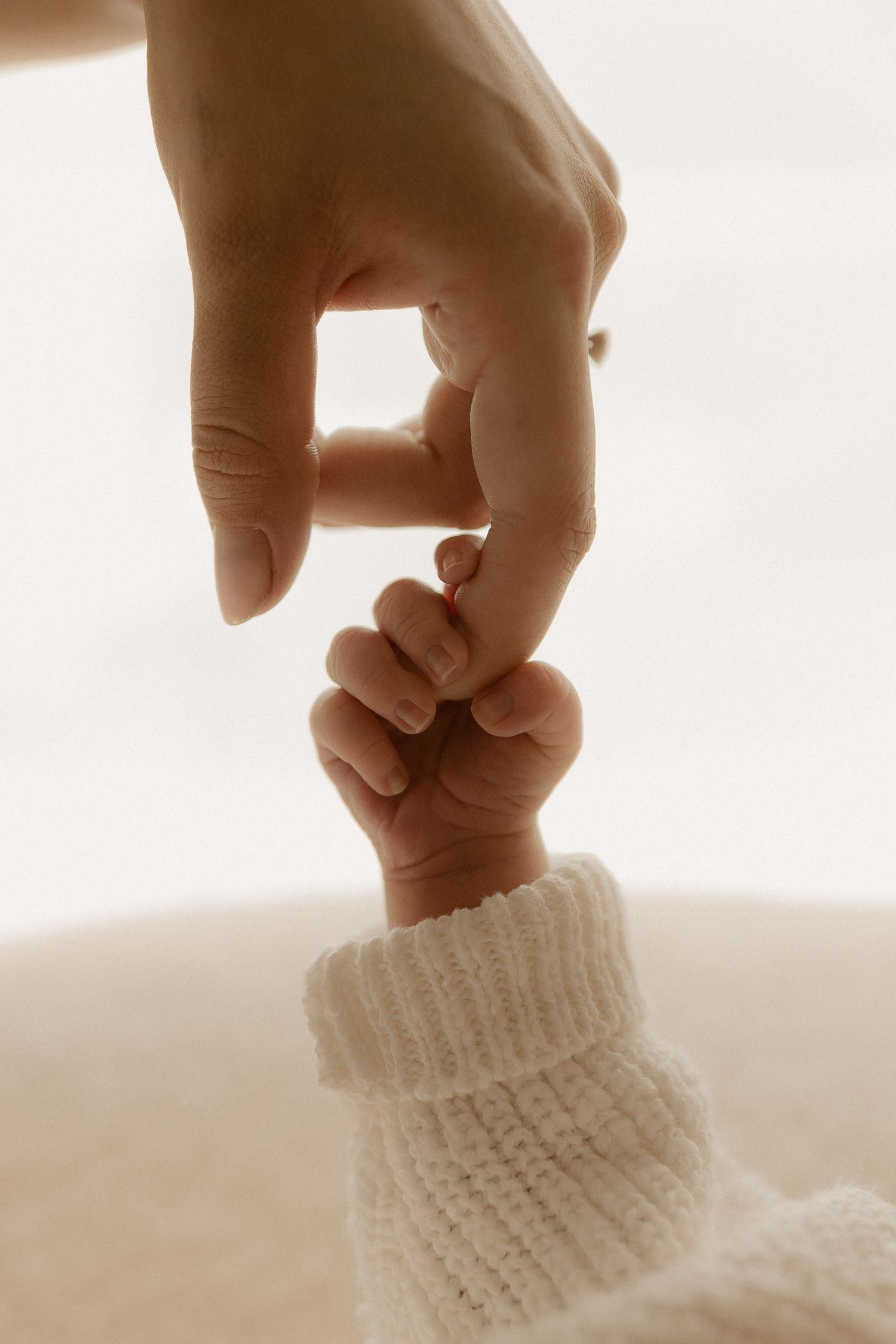 Gentle hands reaching towards delicate white knitted fabric in a series of intimate moments.