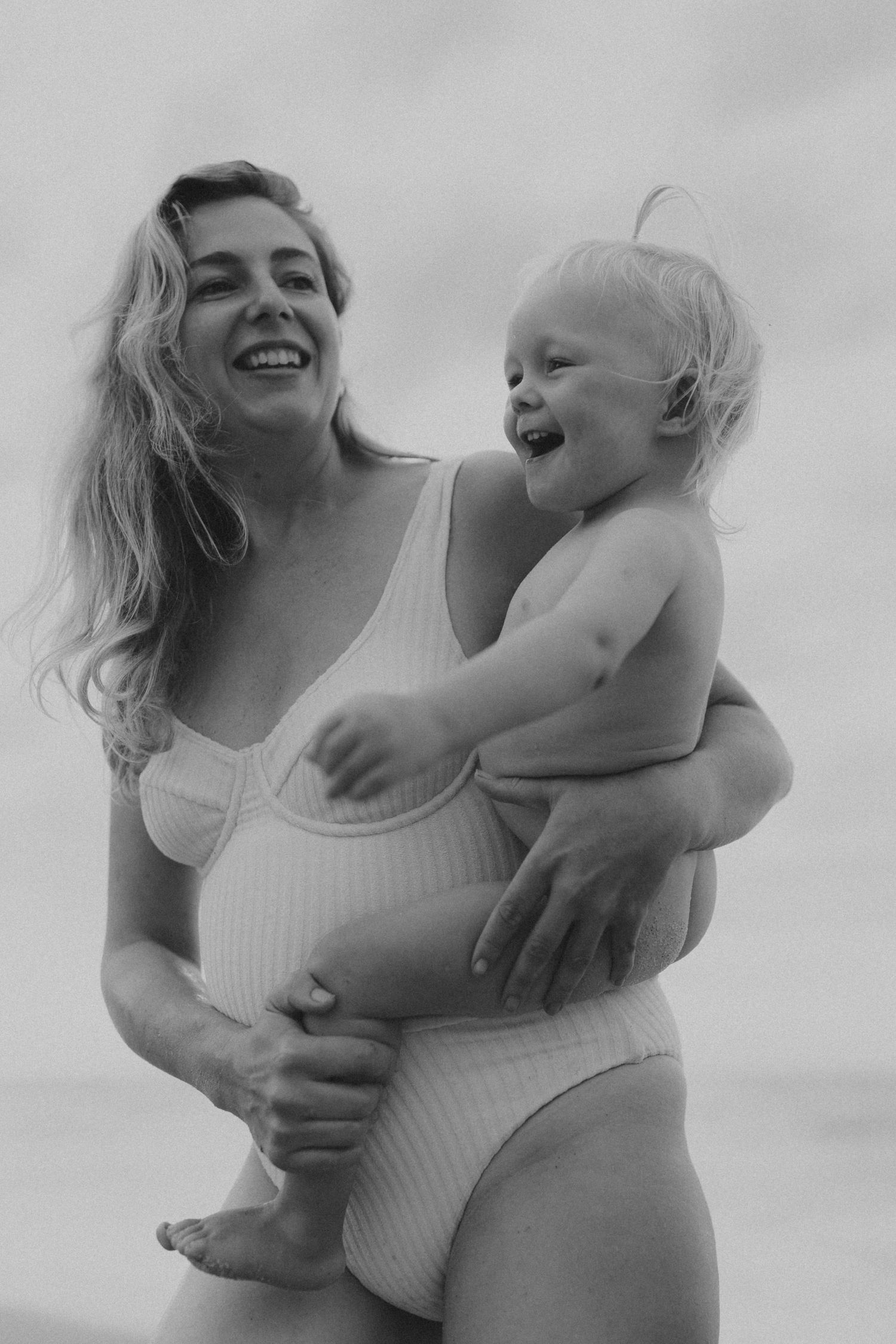 Black and white series of tender moments between parent and child against cloudy sky.