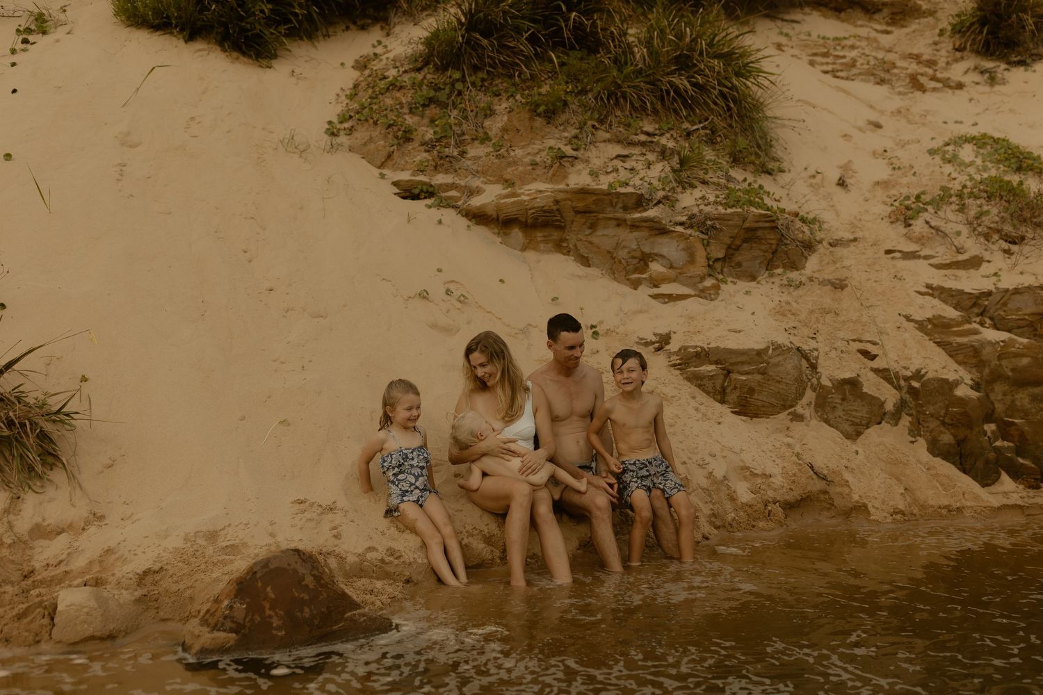 People enjoy swimming and relaxing at a natural swimming hole surrounded by rocky cliffs on a sunny day.
