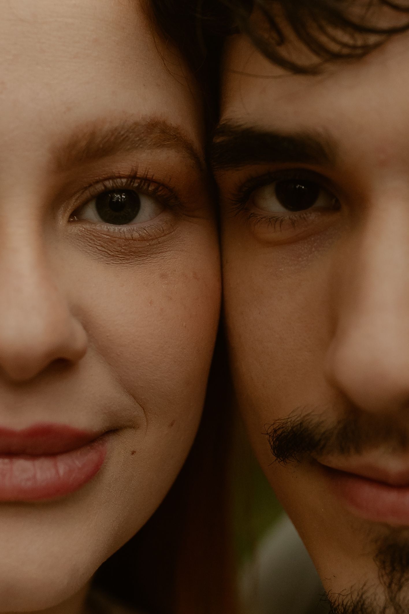 Close-up portrait of a couple smiling together with warm lighting and soft focus.