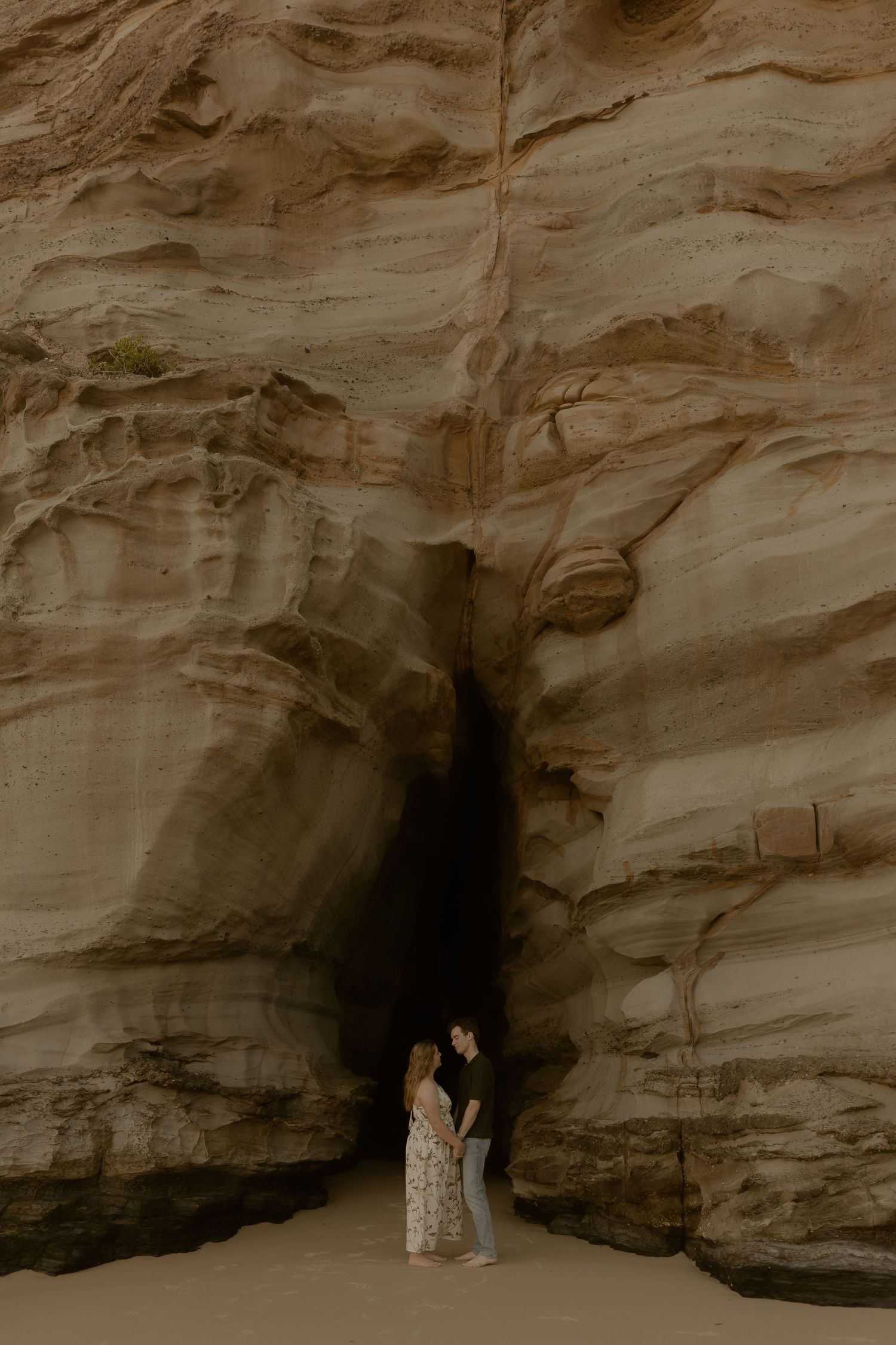 Romantic moment captured against dramatic rocky cave formations at the beach.