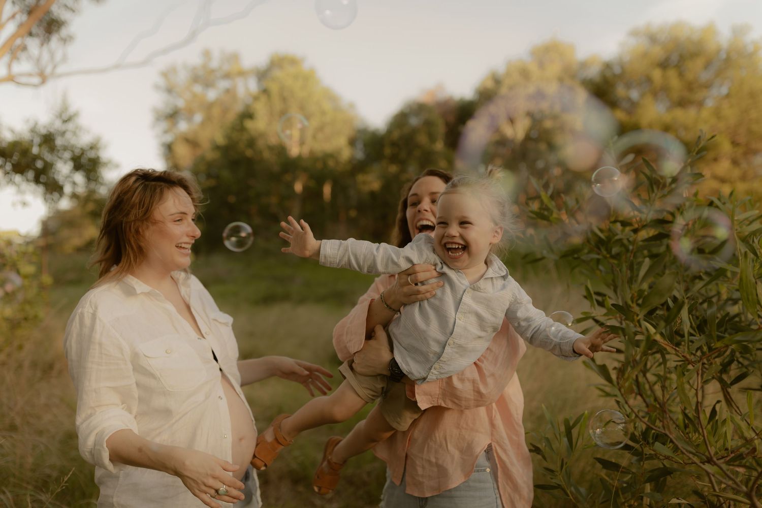 A couple shares joyful laughter together during an outdoor photoshoot in warm autumn lighting.