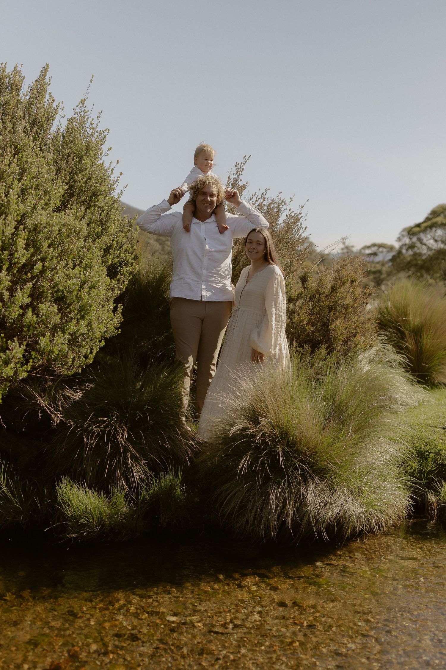 A couple playfully interacts among ornamental grasses in a natural outdoor setting.