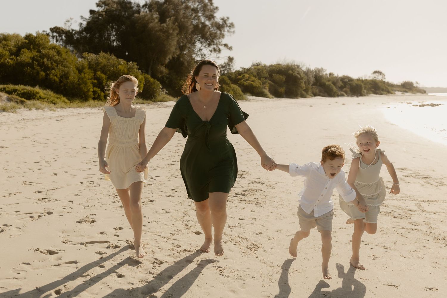 People walking and playing together on a pristine sandy beach at sunset.