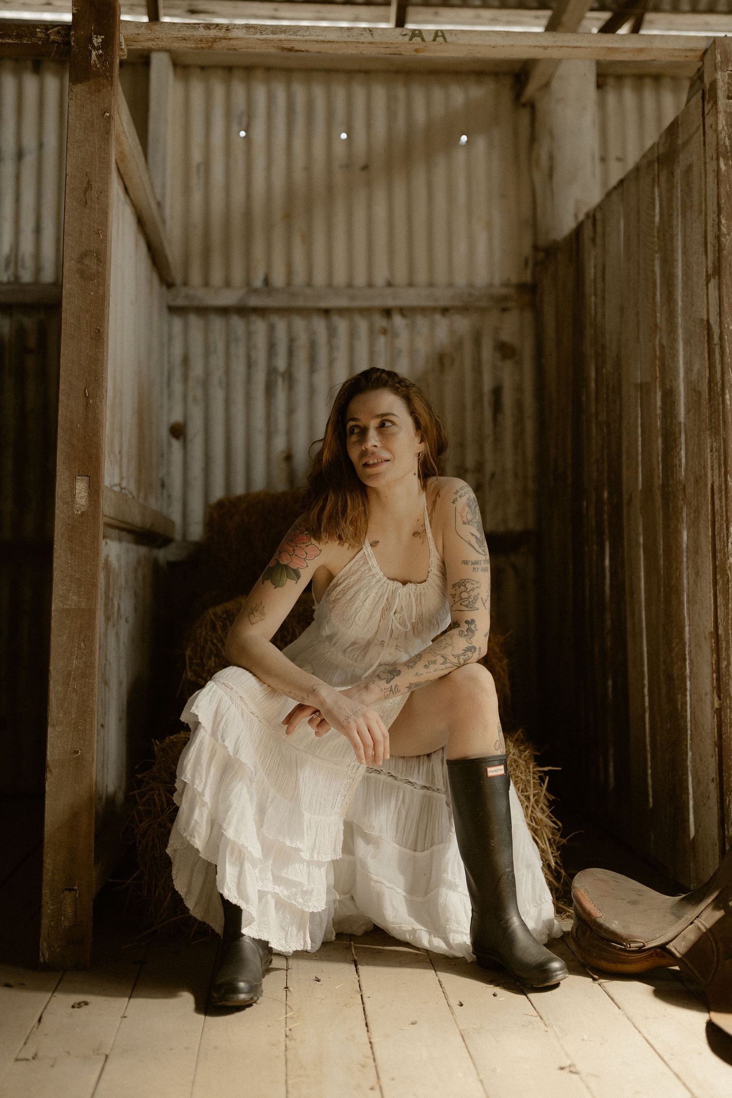 A vintage-style portrait shows someone resting on wooden floorboards in an rustic barn interior.