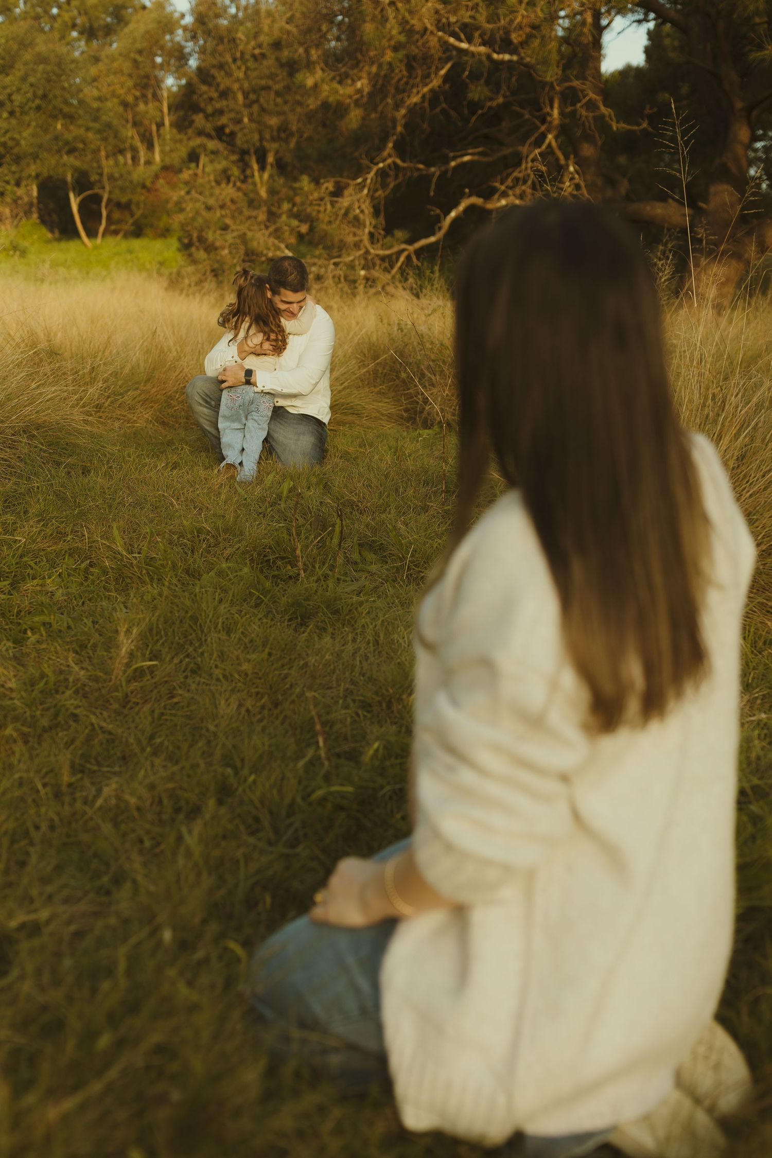 Photographer capturing moment between figures in golden grass field at sunset.