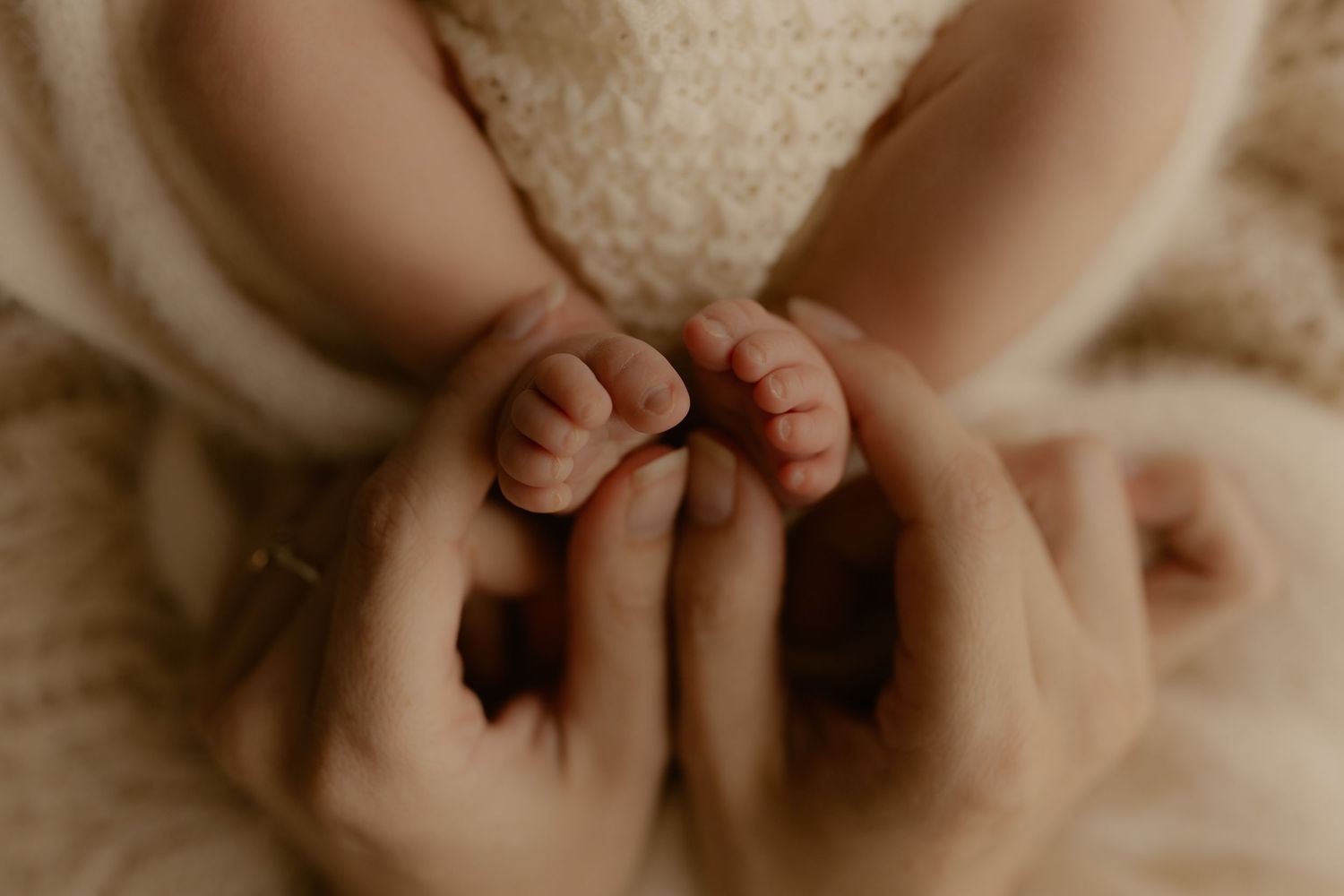 A series of close-up shots showing baby feet and hands in soft, warm lighting against a beige background.