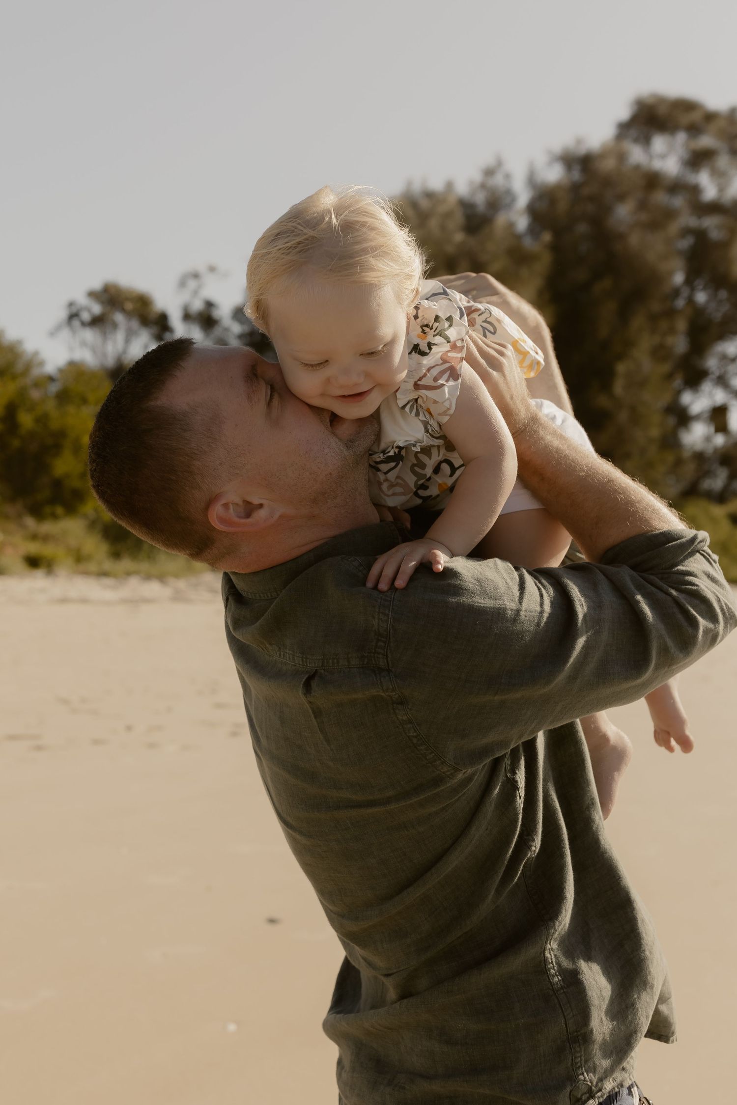 A sweet moment between parent and child sharing affection on a sunny beach.
