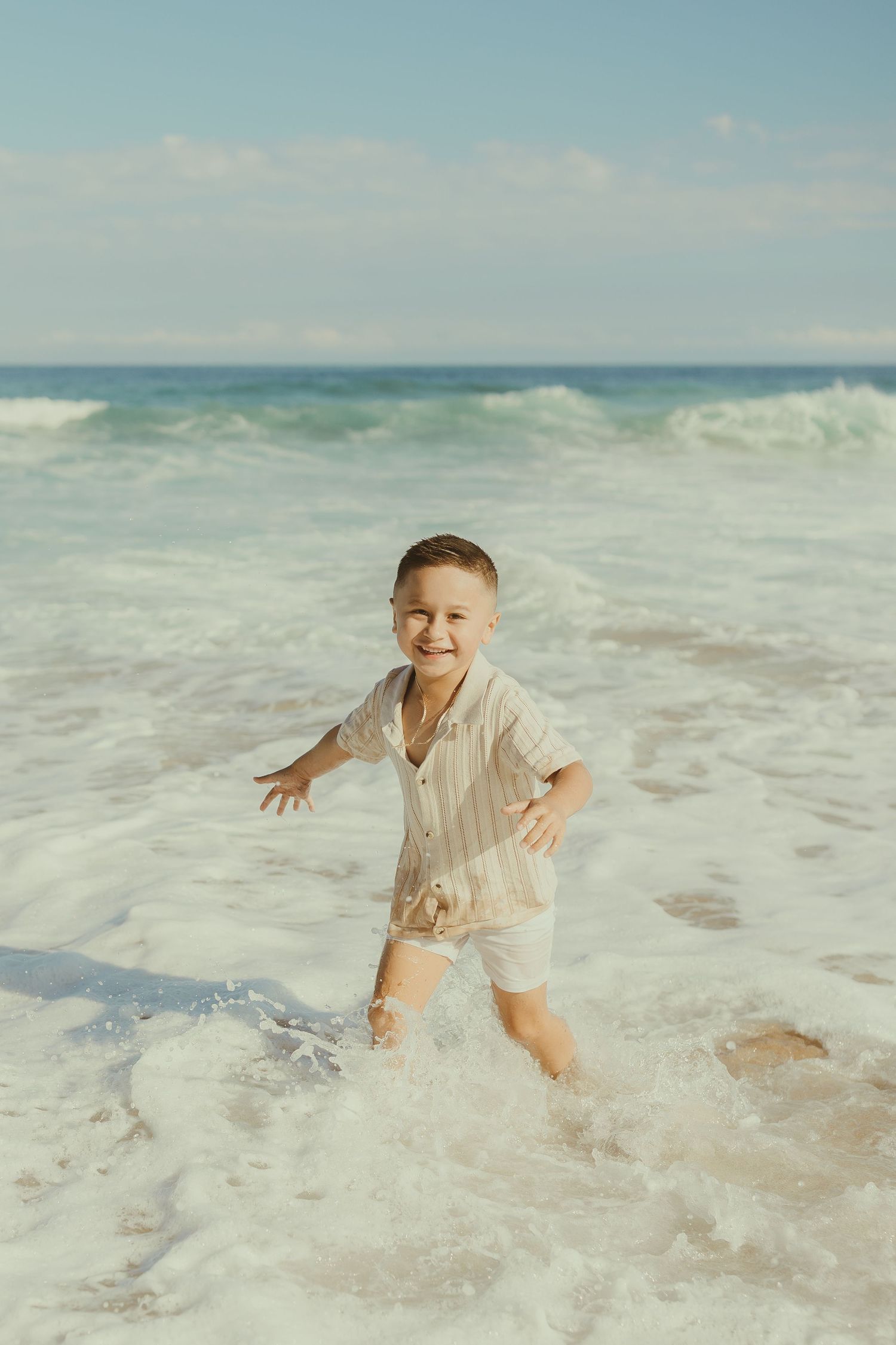 Child playing and splashing in the ocean waves at the beach on a sunny day.