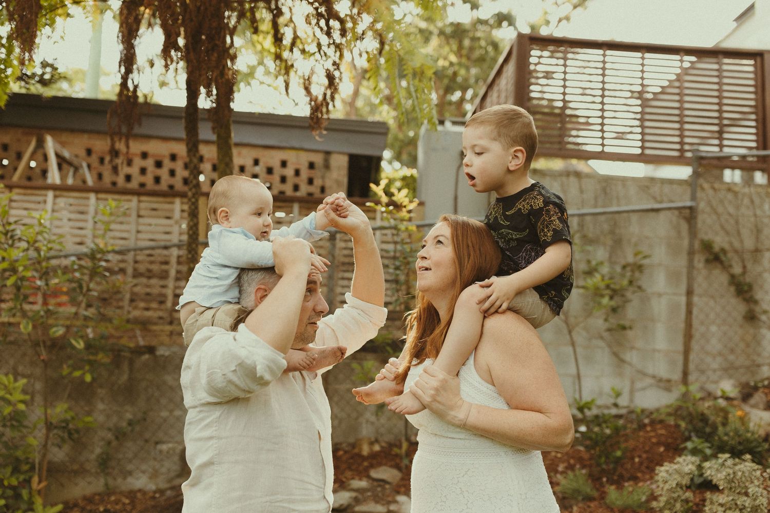 Playful outdoor family photoshoot with everyone making silly faces in a garden.