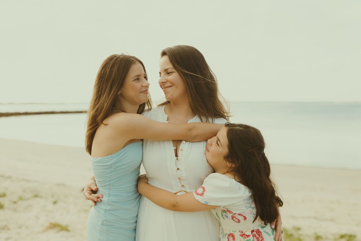 Family members share warm embraces and smiles on a sunny beach.