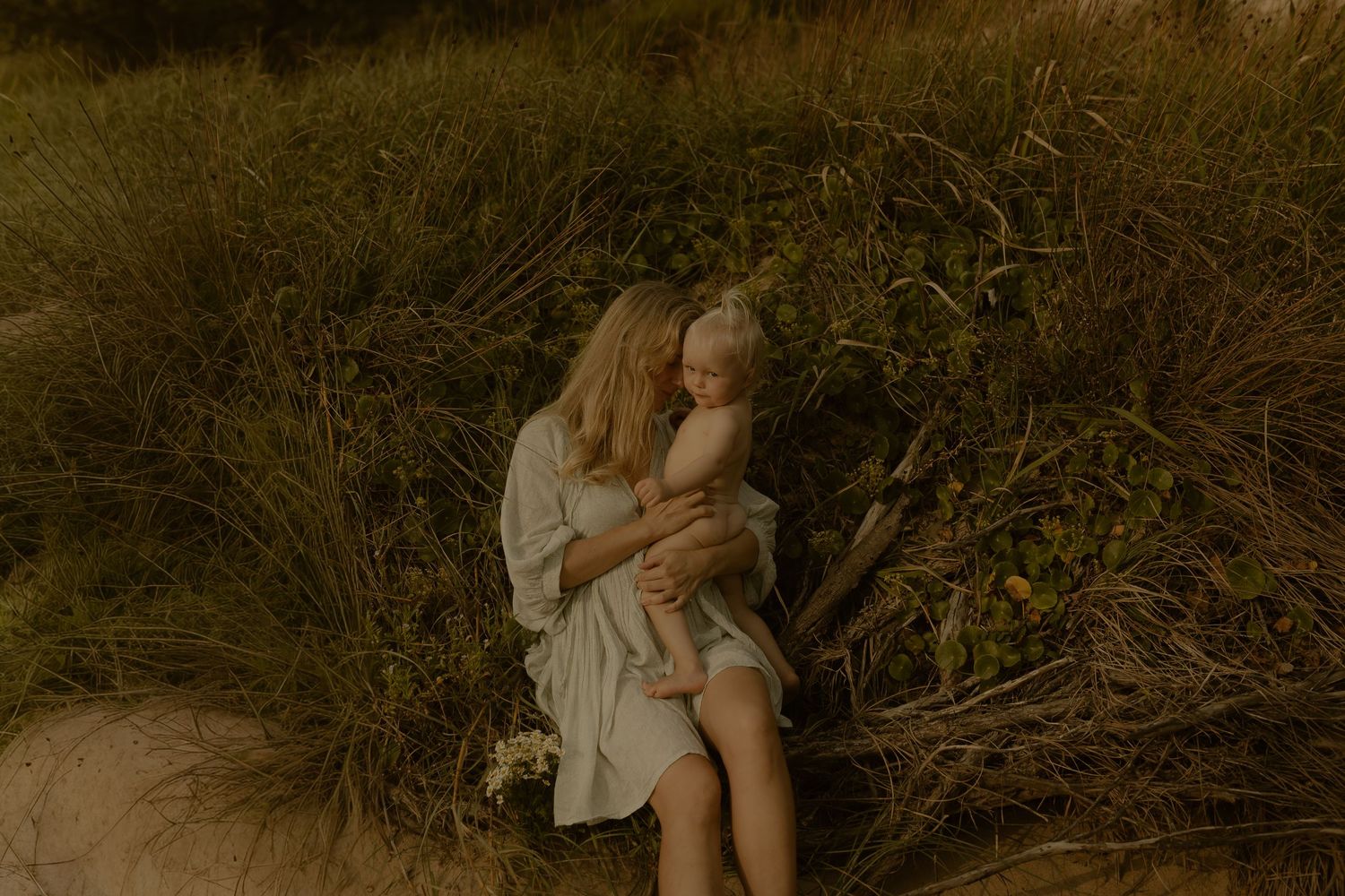 Family sharing quiet moments together in tall grass at dusk.