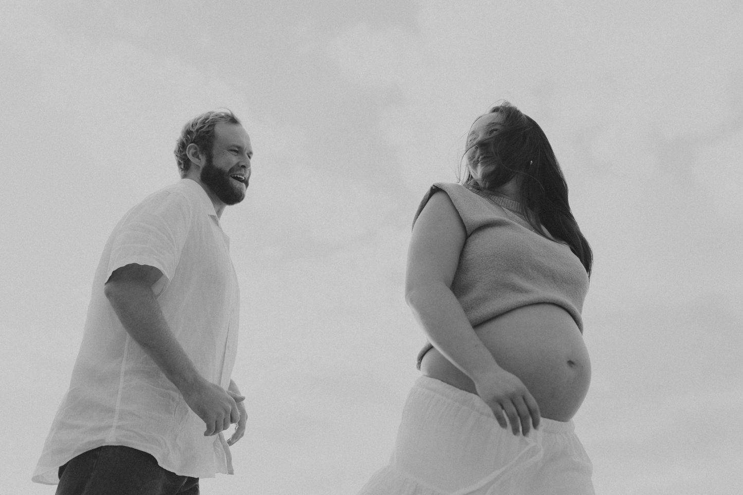Black and white photo of couple laughing together on misty beach.