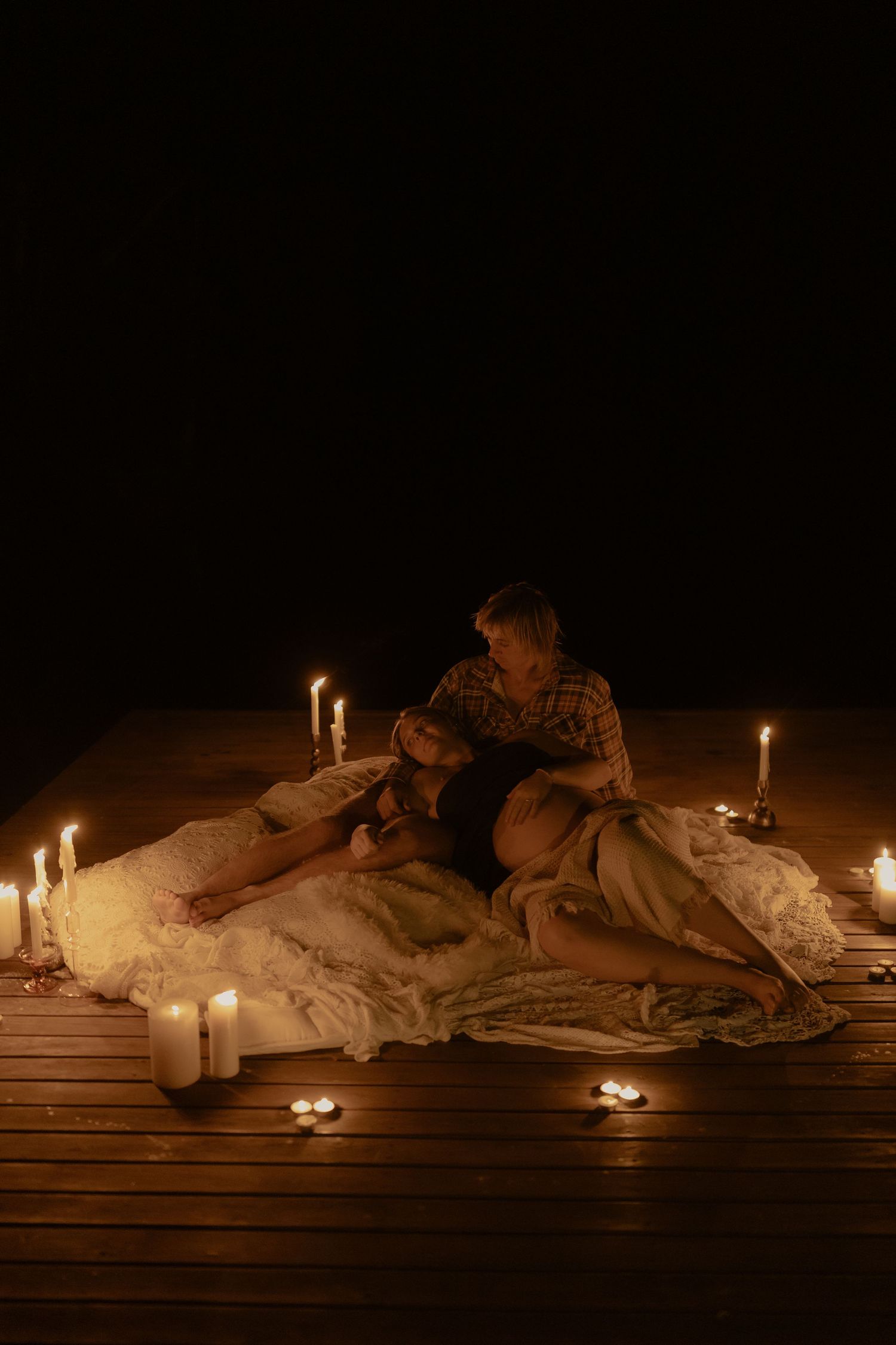 Candlelit scene with white linens and blankets creating a cozy romantic atmosphere.