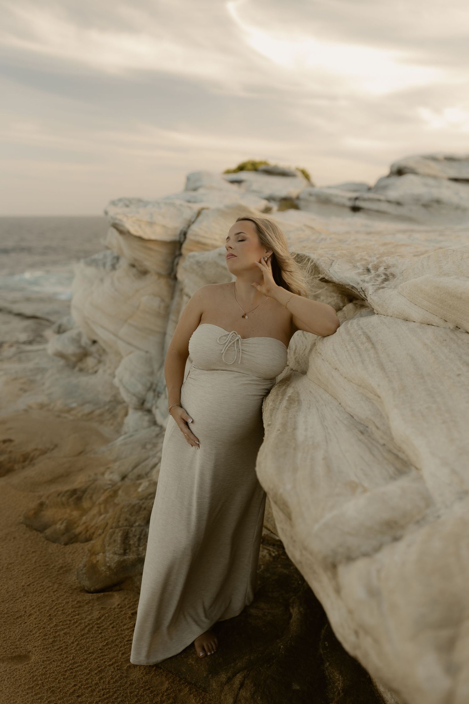 Dreamy beach wedding photography with elegant poses against natural rock formations.