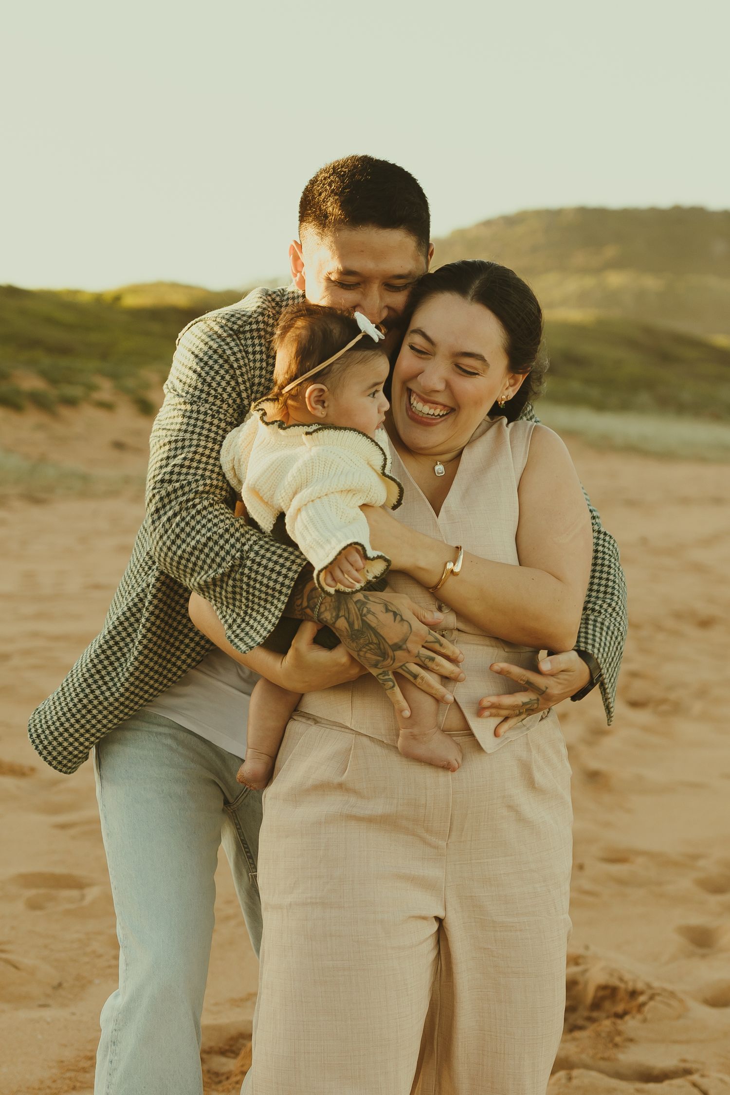 Tender moments captured in a series of warm sunset photos showing a couple and baby sharing affectionate embraces on sandy terrain.