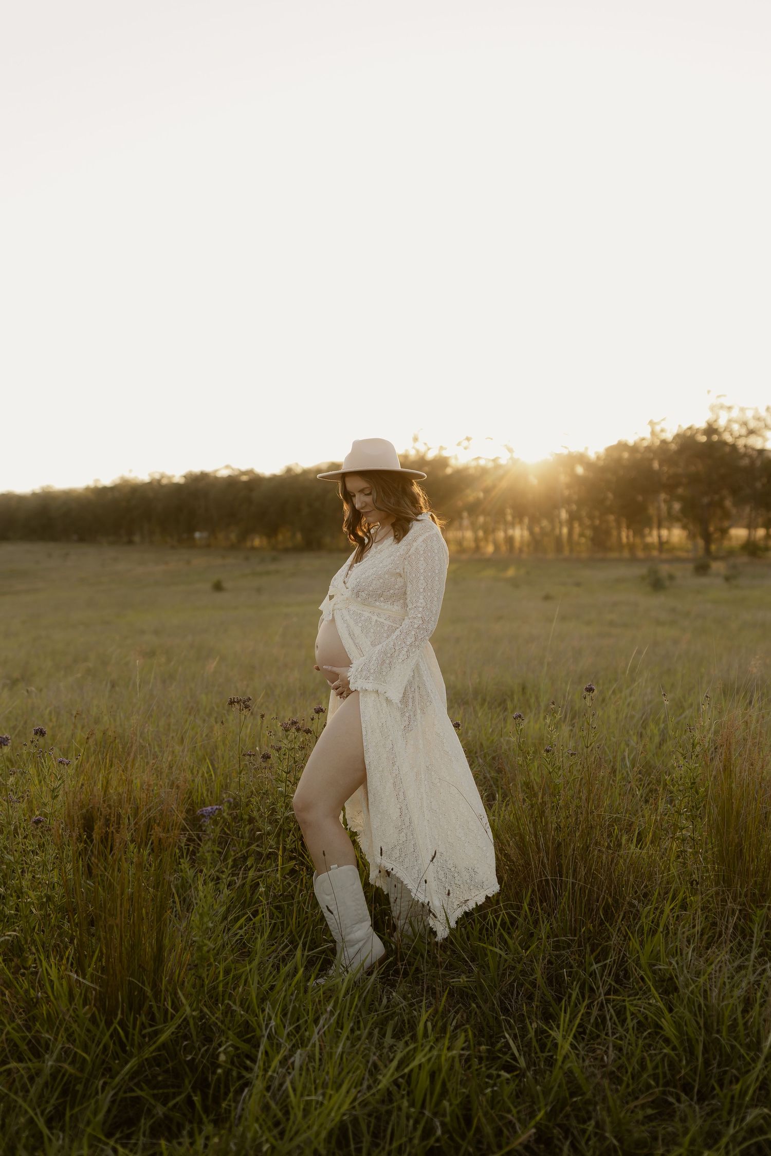 White lace dress flowing in the breeze as someone sits in a grassy meadow at golden hour.