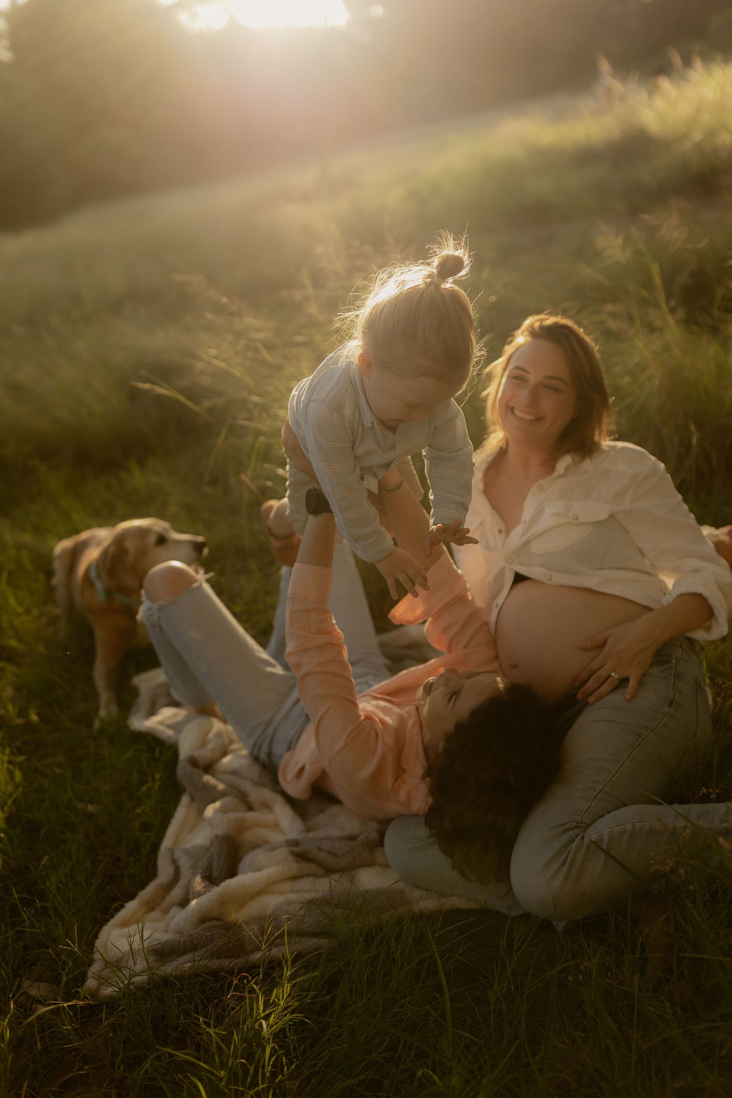 Family lying in grass together during golden hour photoshoot.