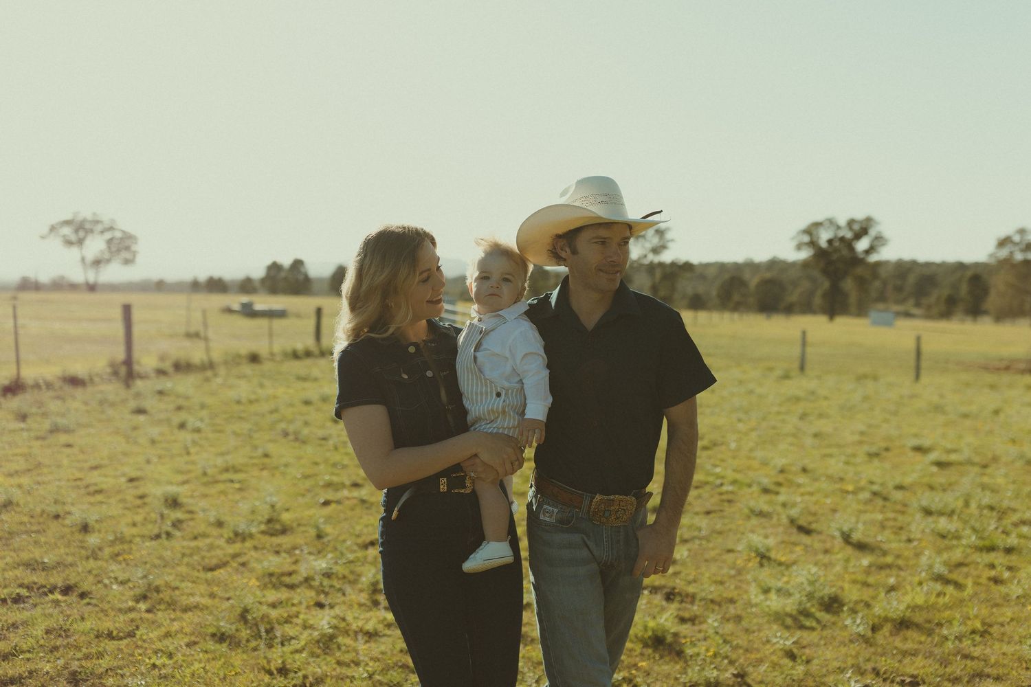 A family shares a tender moment together in a rustic countryside setting at sunset.