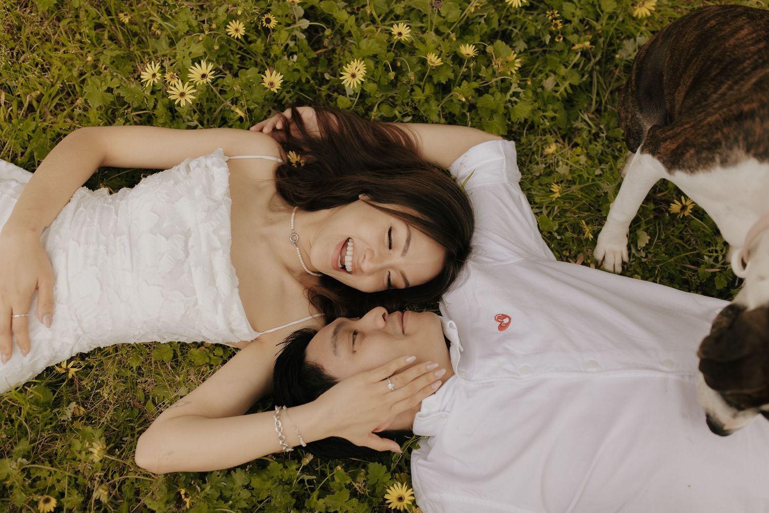 Person in white dress lying gracefully on grass among yellow wildflowers.