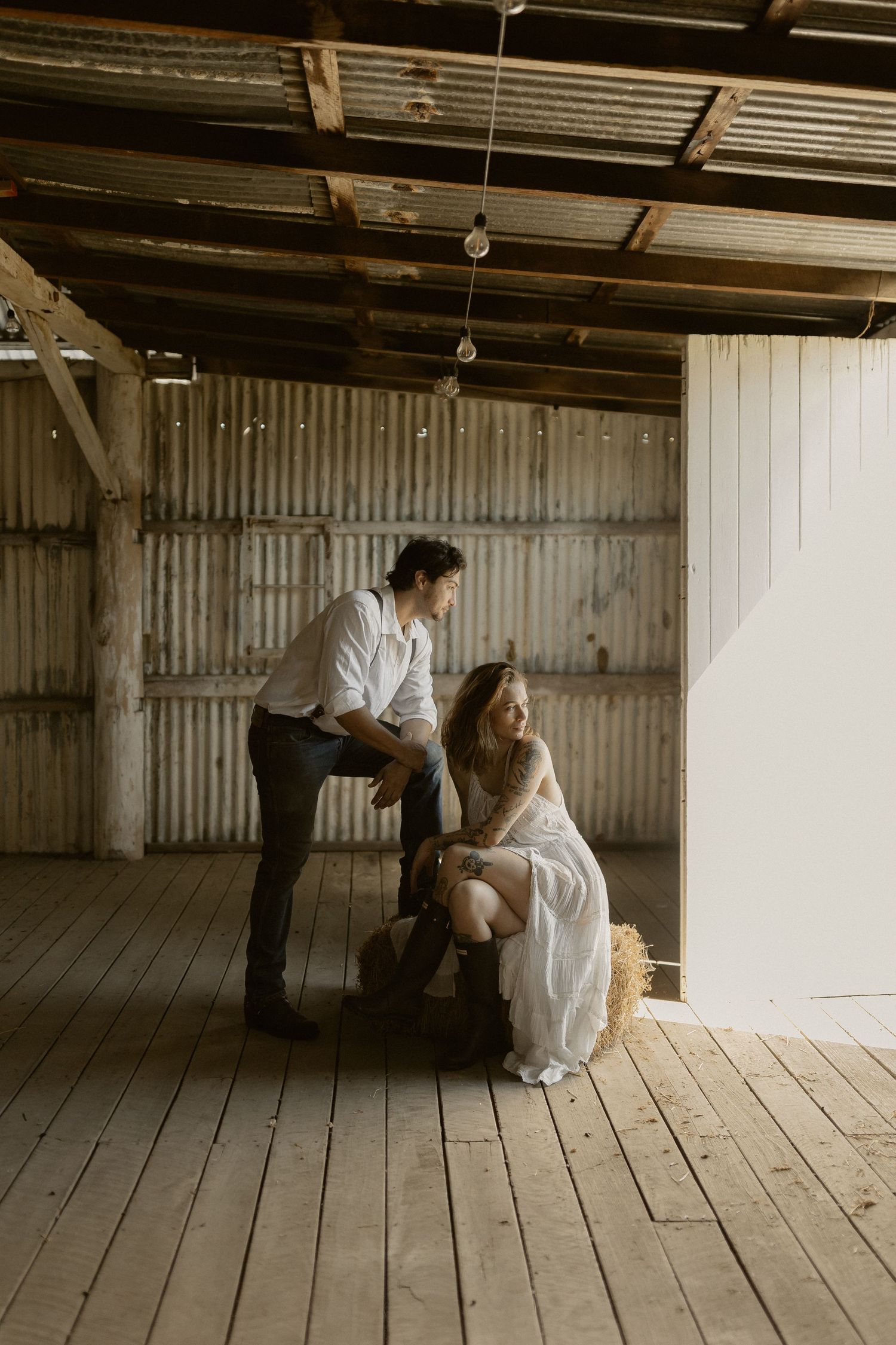 Intimate moment captured in rustic barn with wooden floors and metal walls.