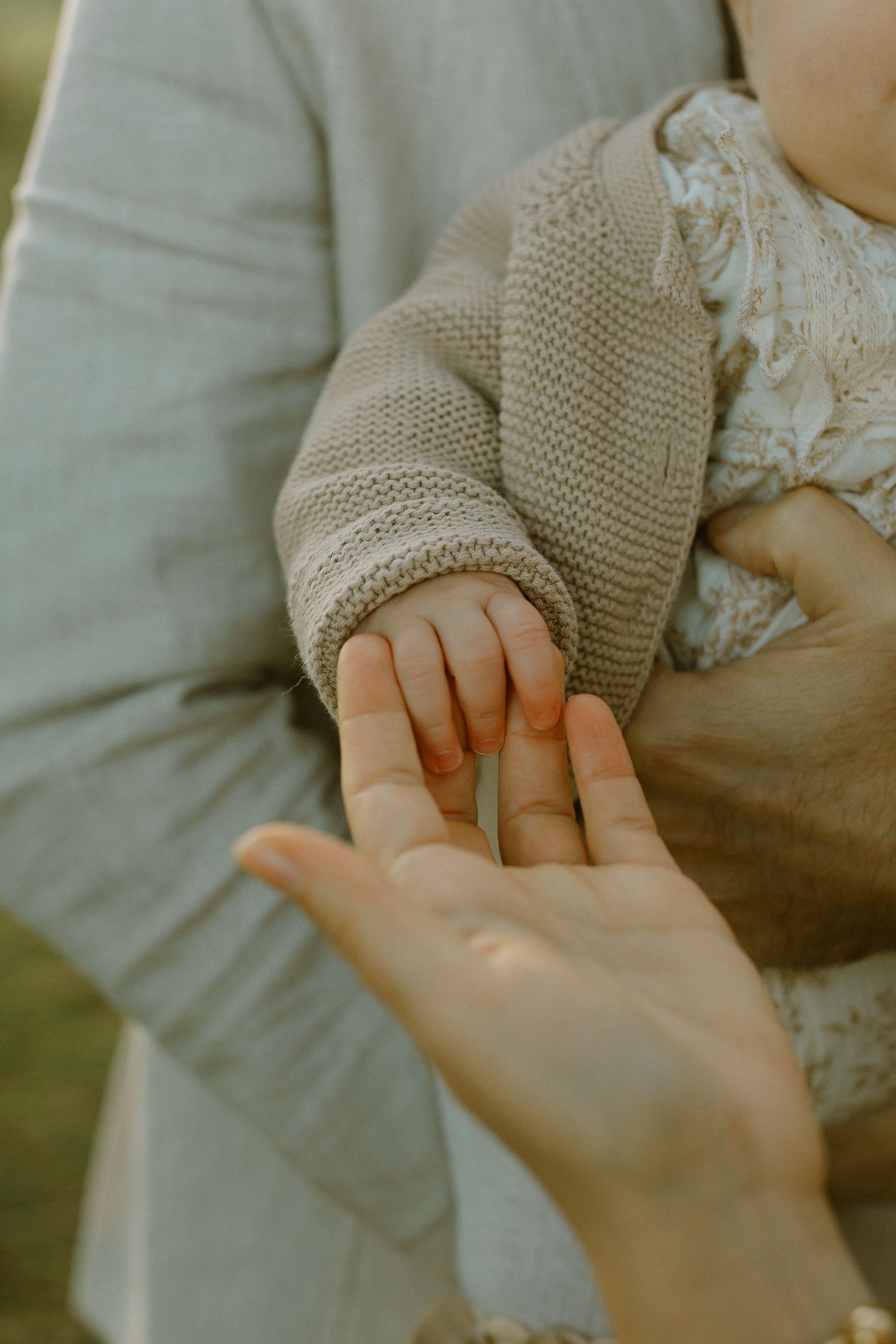 Close-up shot of a small hand reaching to touch an adult's palm.