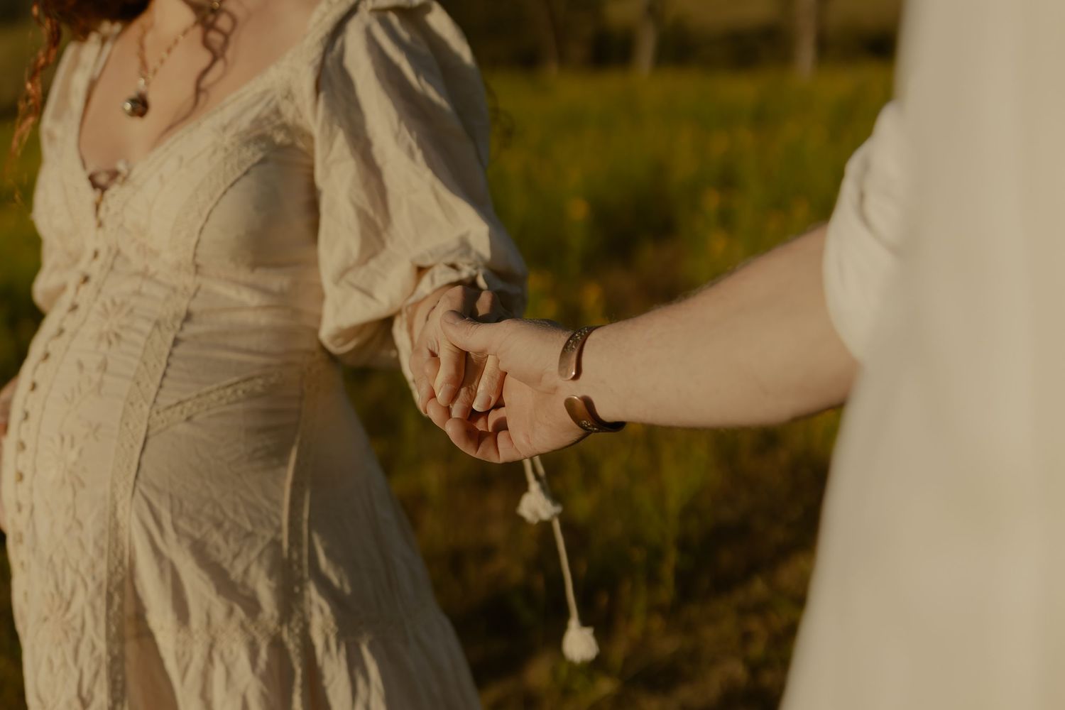 A couple shares an intimate moment in golden sunlight wearing light-colored clothing.