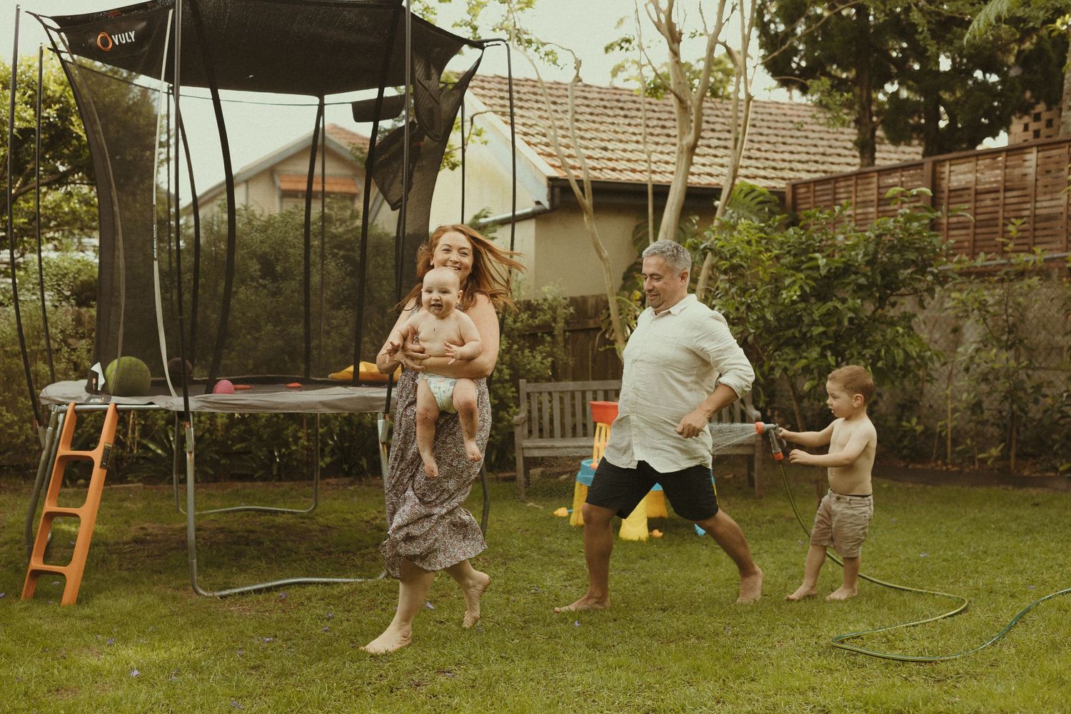 Family enjoying outdoor playtime with swings and activities in a backyard setting.