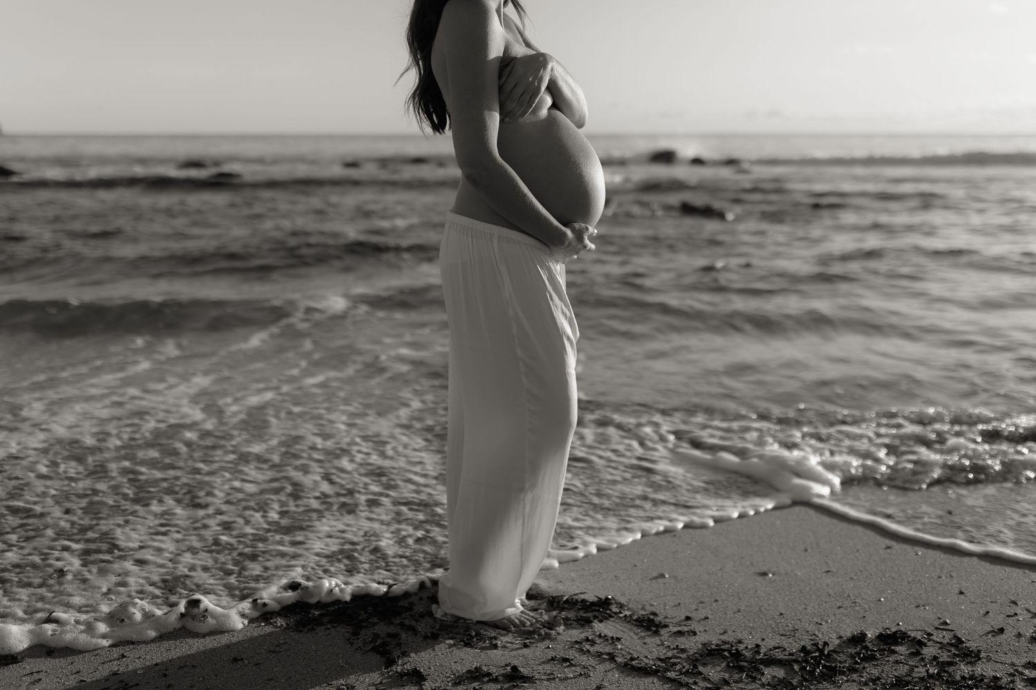 A collection of black and white beach photos showing people walking along the shoreline at sunset.