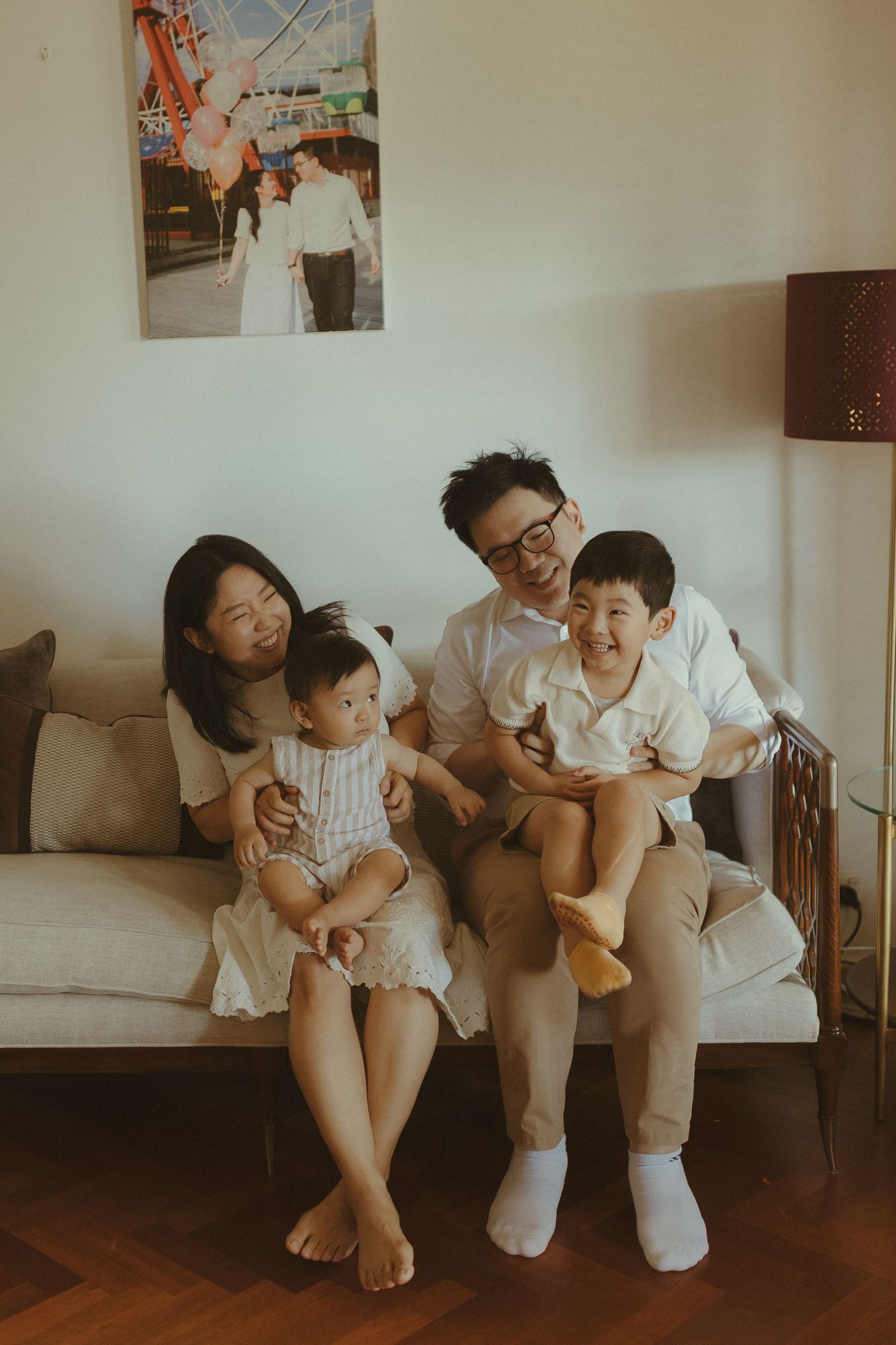 A family shares a joyful moment together while sitting on a gray couch in their living room.