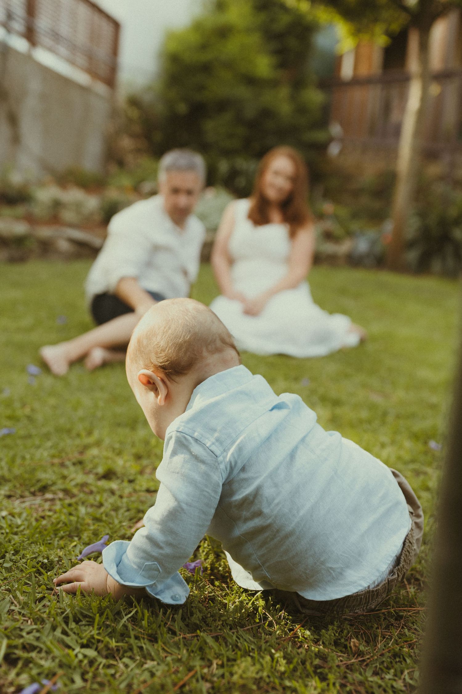 A baby crawling on grass during an outdoor photo session with a dreamy, vintage look.