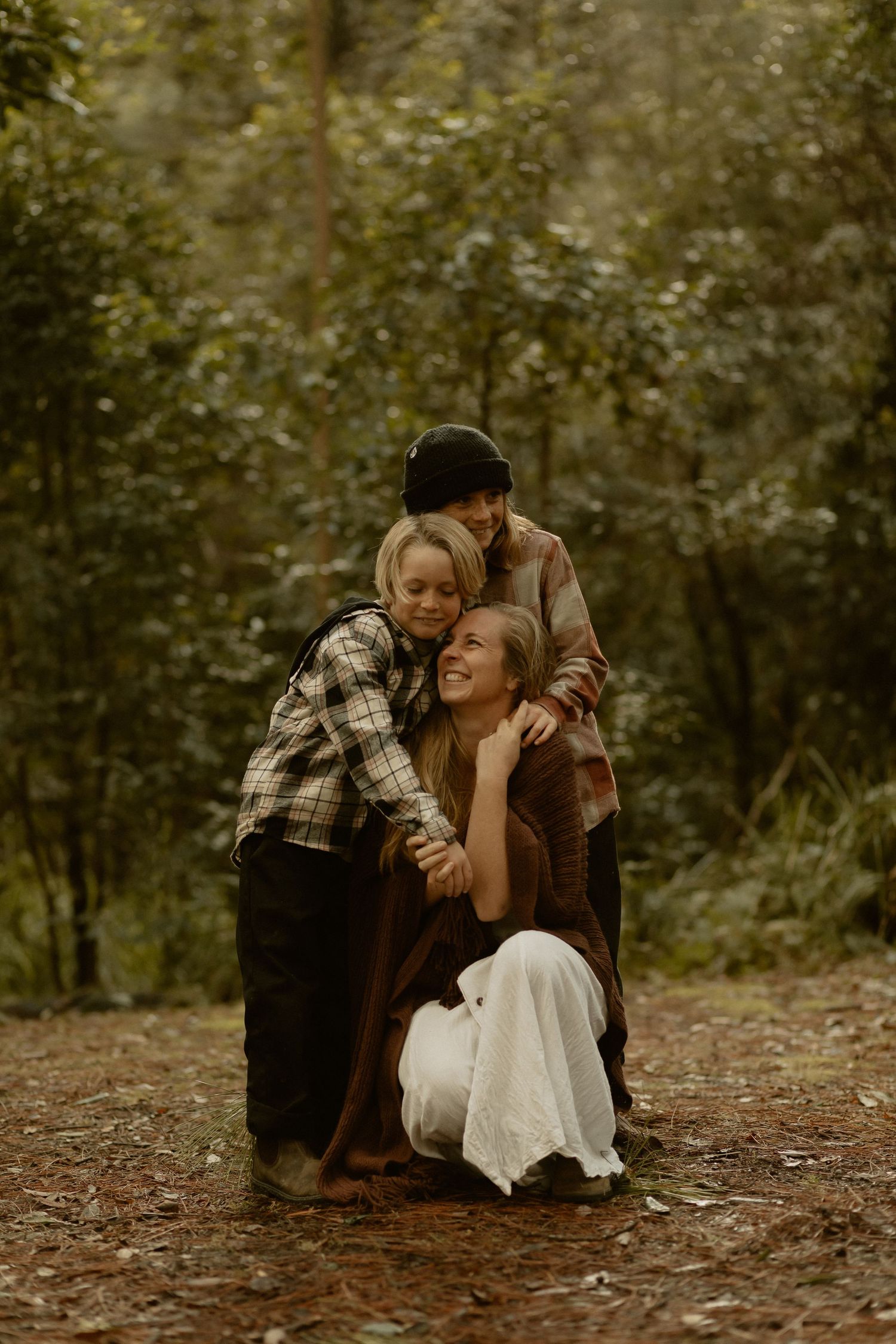 A candid moment of laughter and embrace in an autumn forest setting with warm earth tones and natural lighting.
