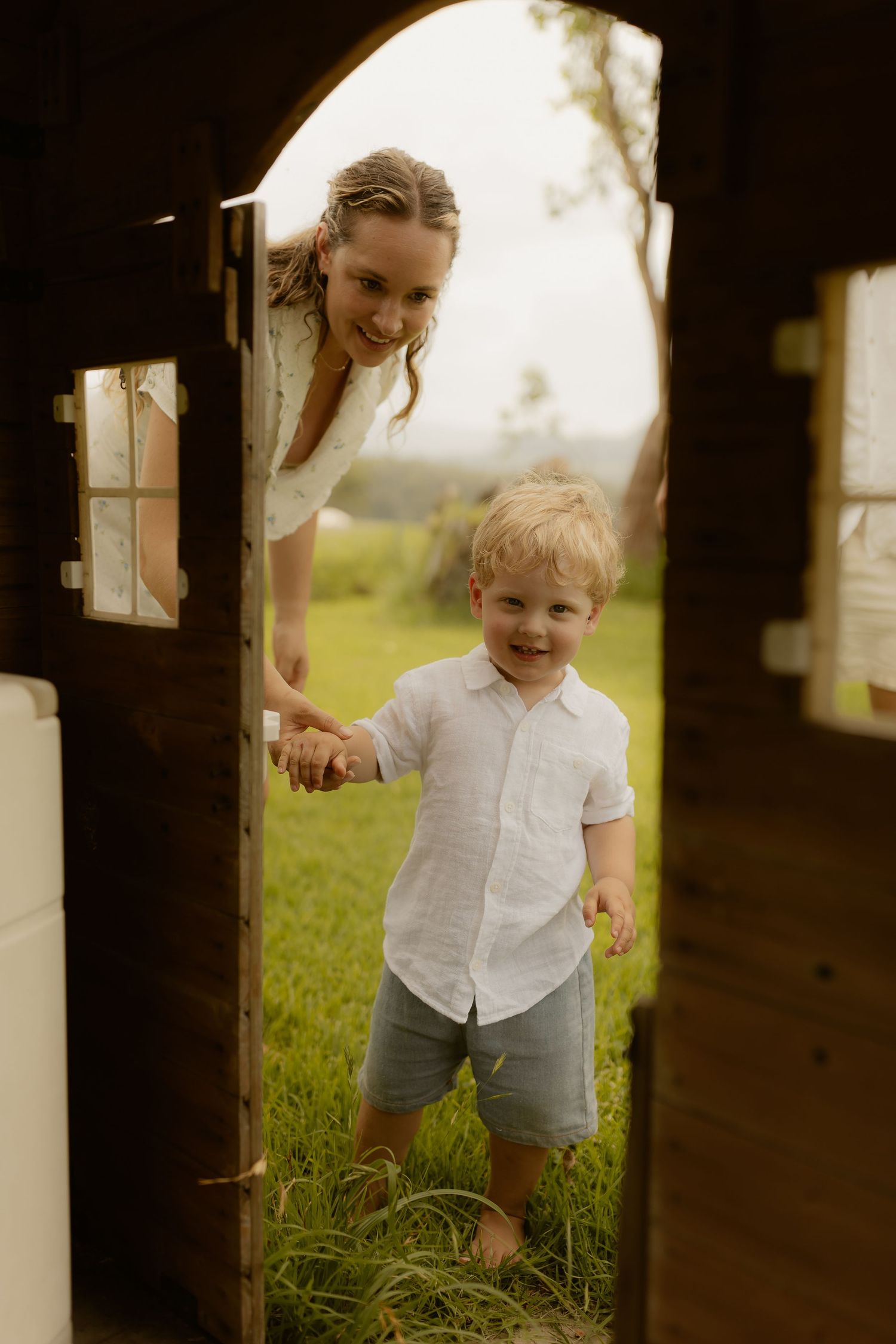 Playful moment captured through wooden frame as child runs through grass.