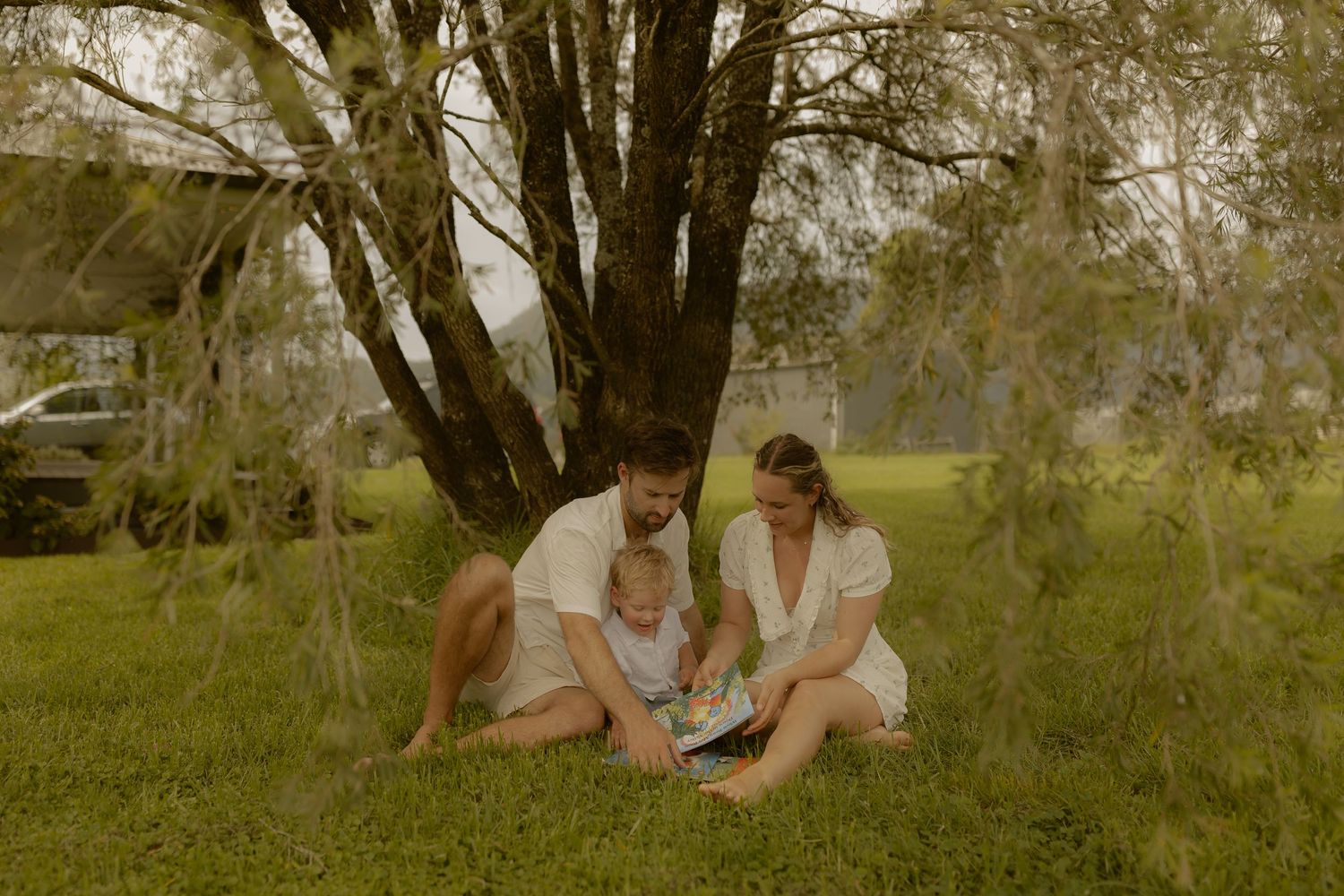 A tender embrace captured in a garden with trees and flowers in the background.