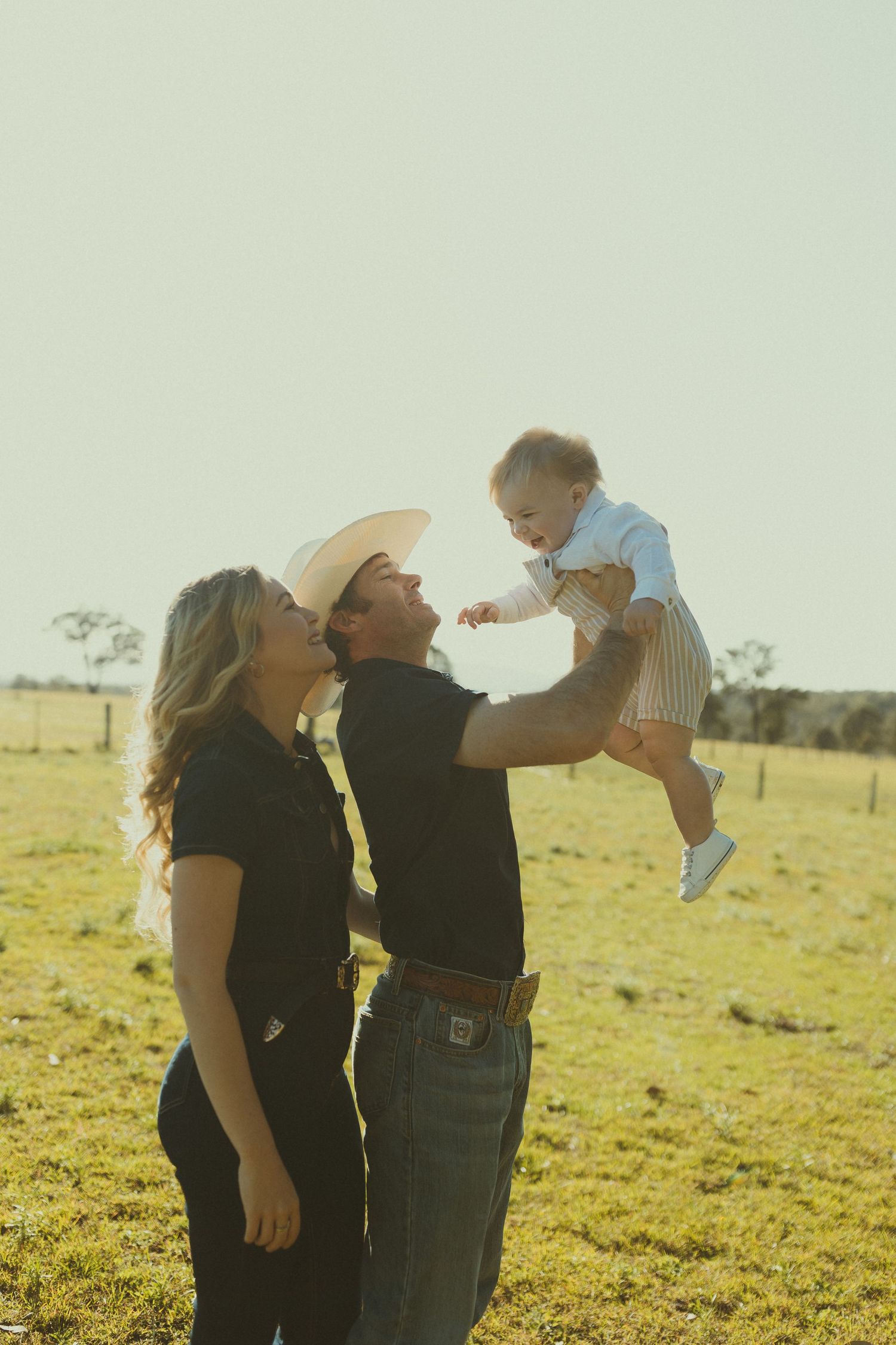 A family shares a tender moment together in a sunlit field during golden hour.