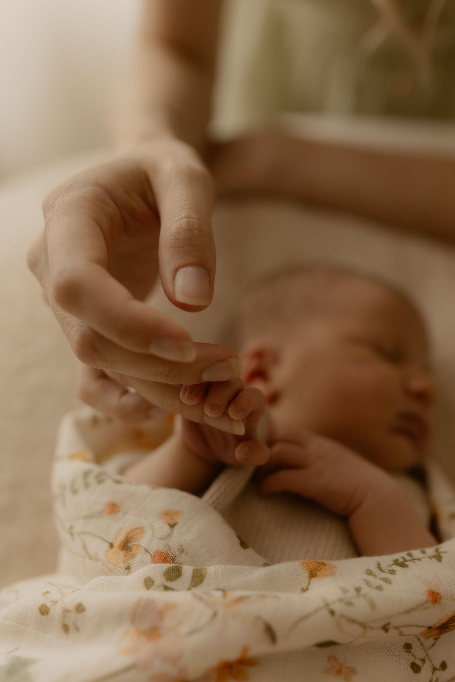 Close-up of tiny baby hands and feet on floral patterned fabric.