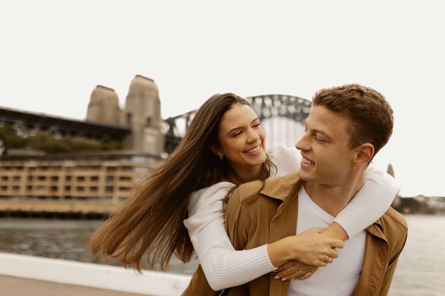 Happy couple sharing joyful moment near Sydney Harbour Bridge.