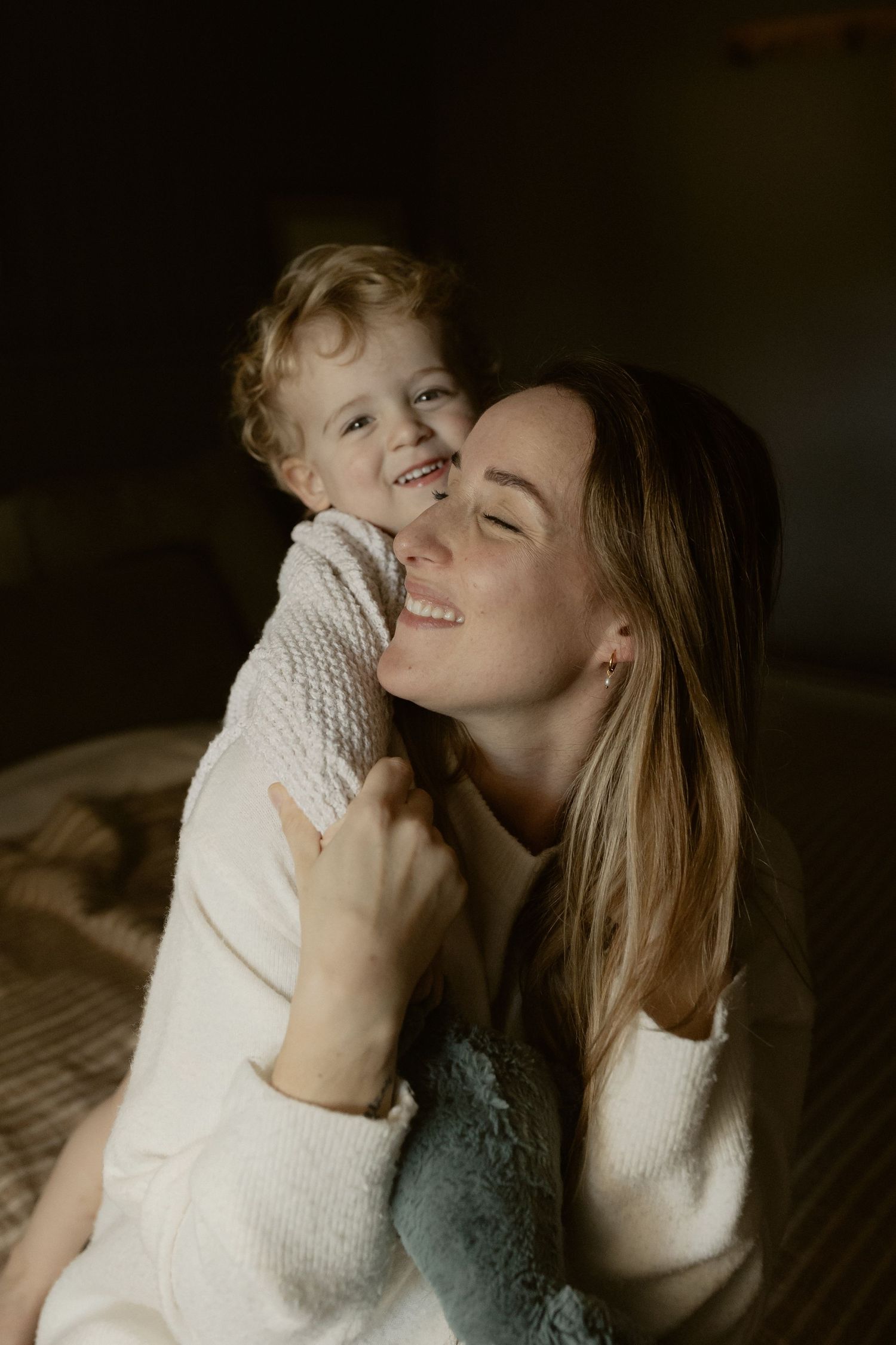 Joyful candid moment captured between parent and child wearing matching white knit sweaters.