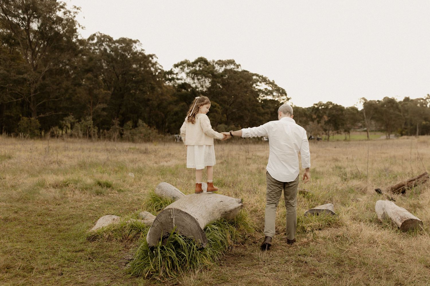 Light brown muted toned images show a family enjoying time together in a grassy field.