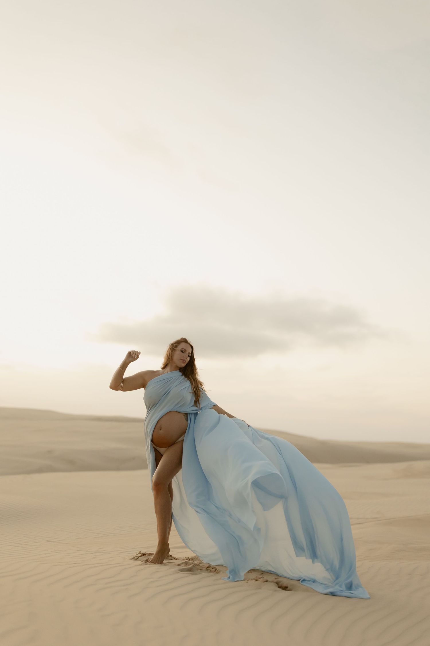 Artistic desert portraits featuring a flowing blue dress against sandy dunes in soft light.