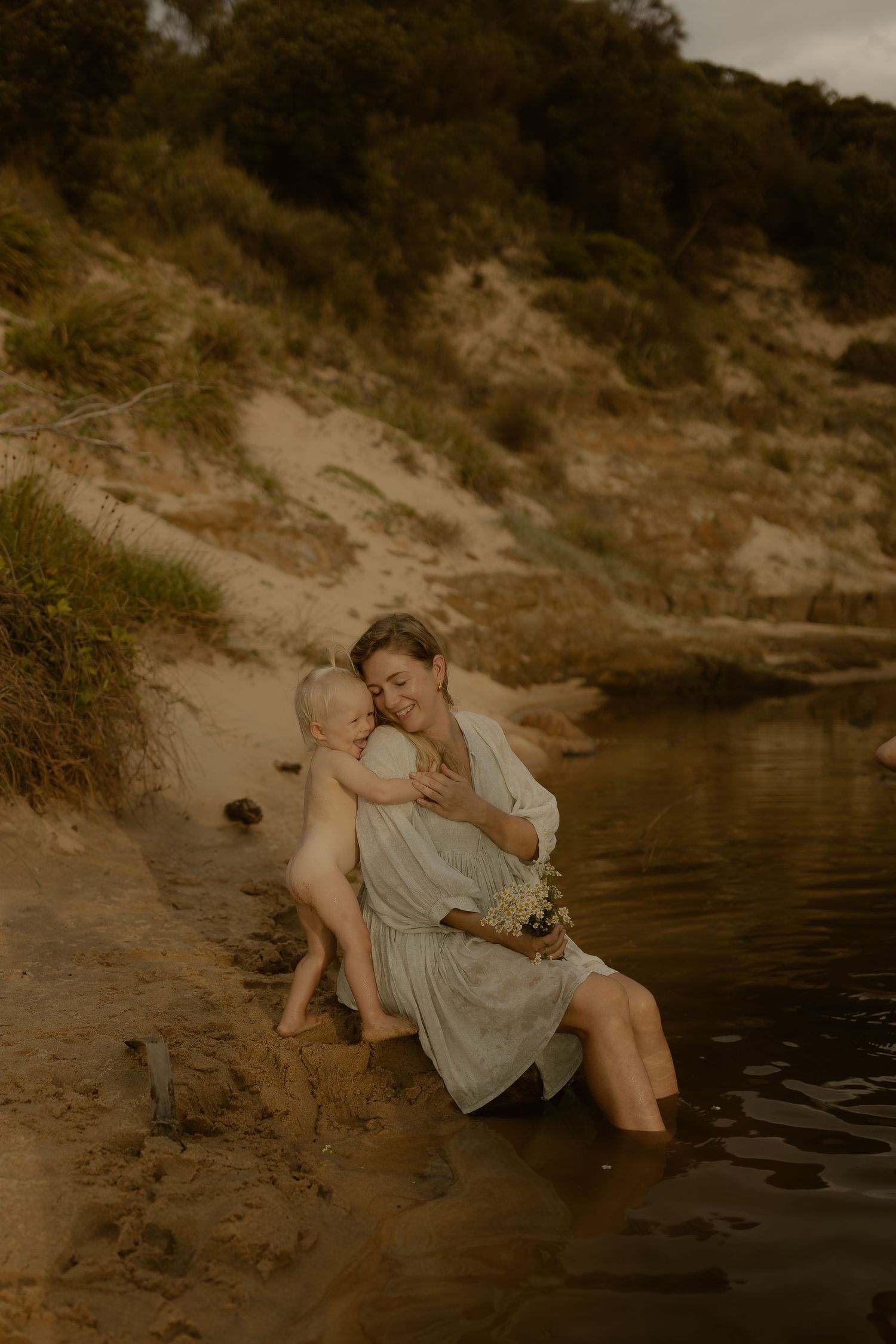A dreamy sepia photograph of figures sitting by a tranquil waterside at dusk.
