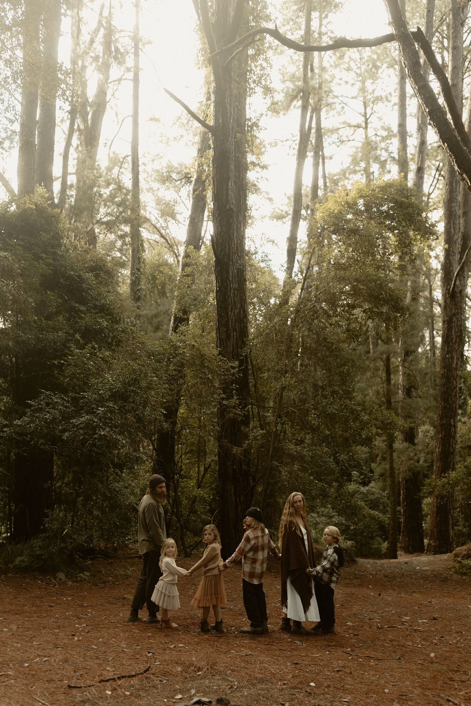 Dreamy forest photography scene with vintage-styled figures among towering pine trees.