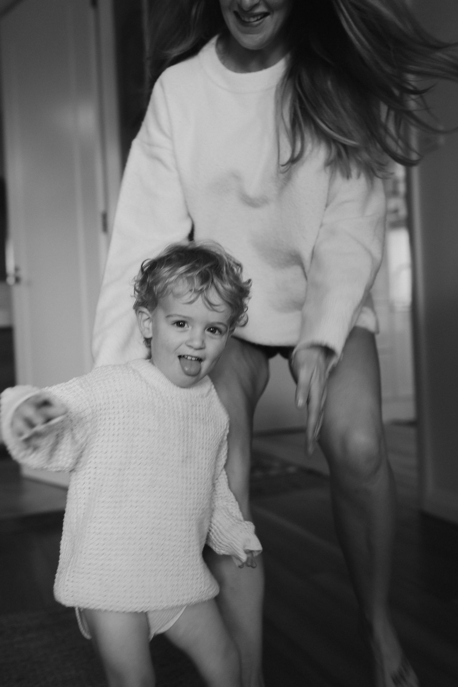 Dynamic black and white sequence of joyful movement and laughter in a home hallway.