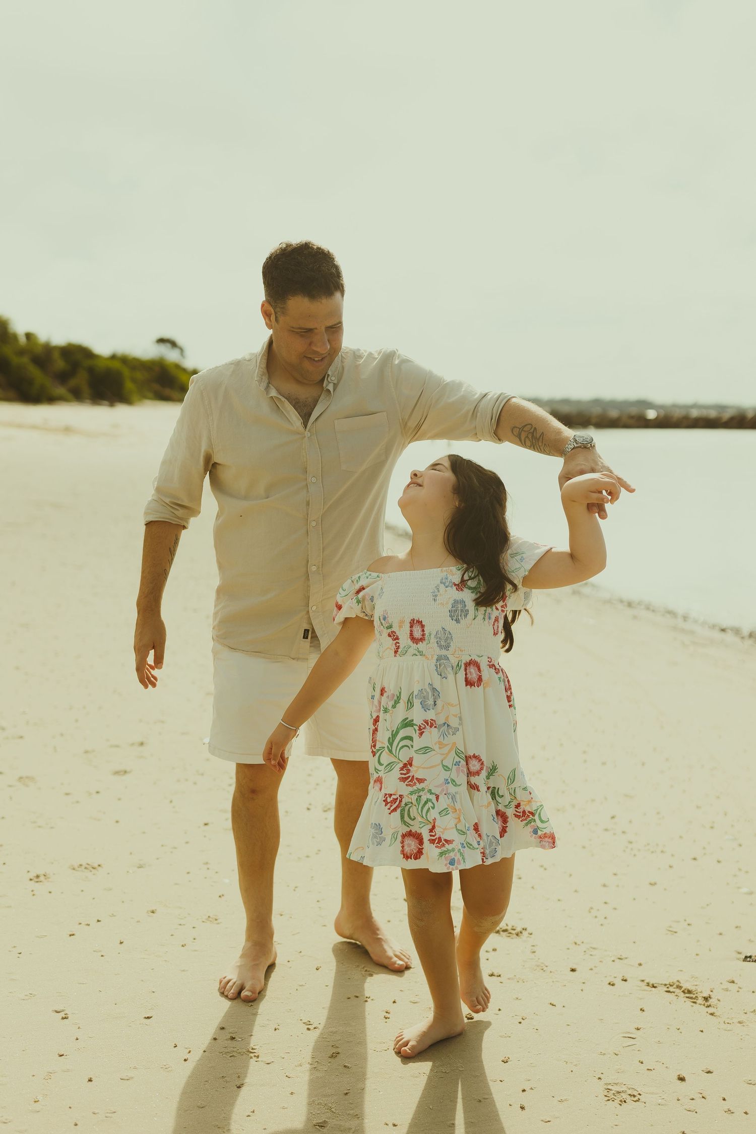 Parent and child dancing together on a beautiful beach.