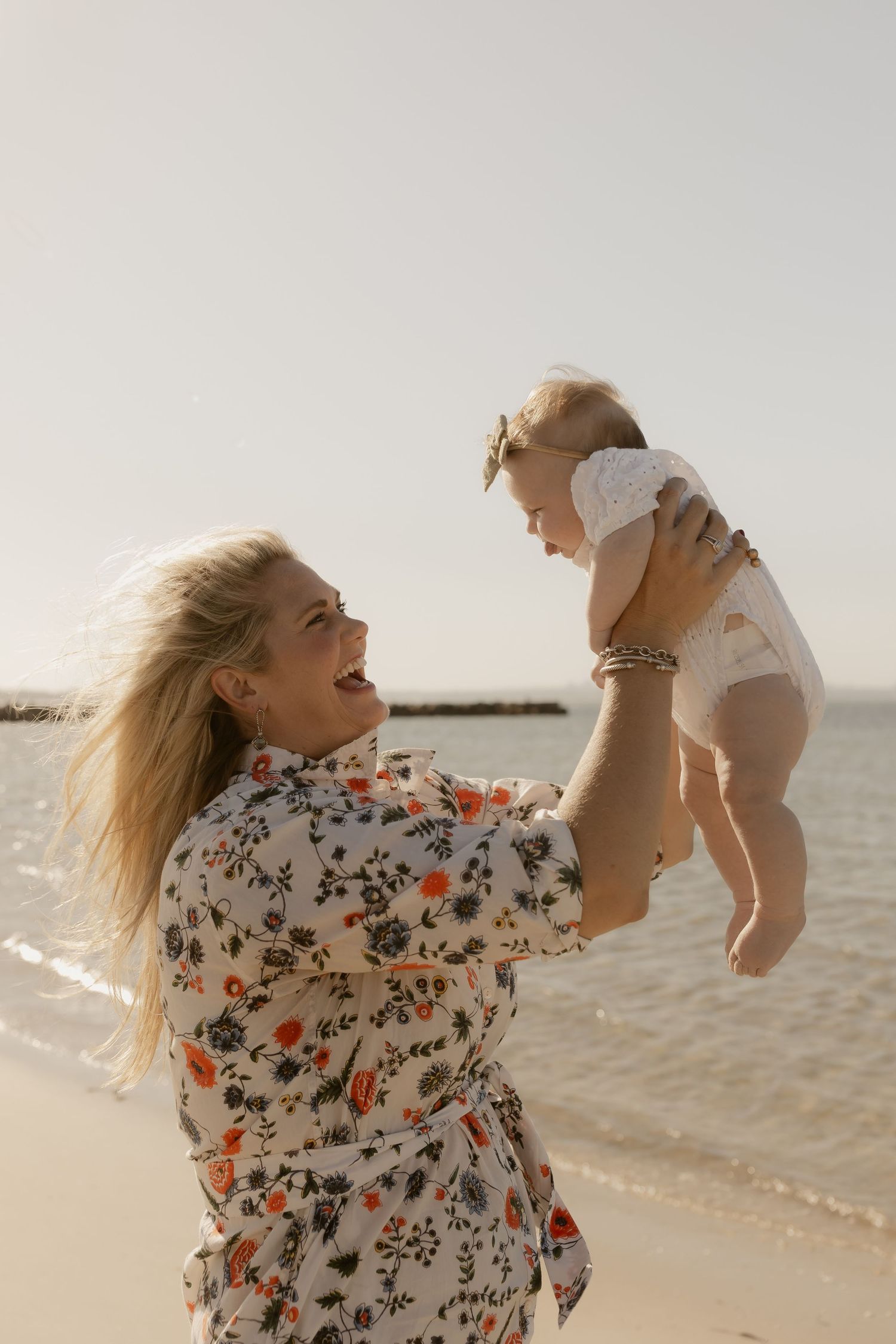 Joyful moments of a parent lifting and playing with a small child on the beach.