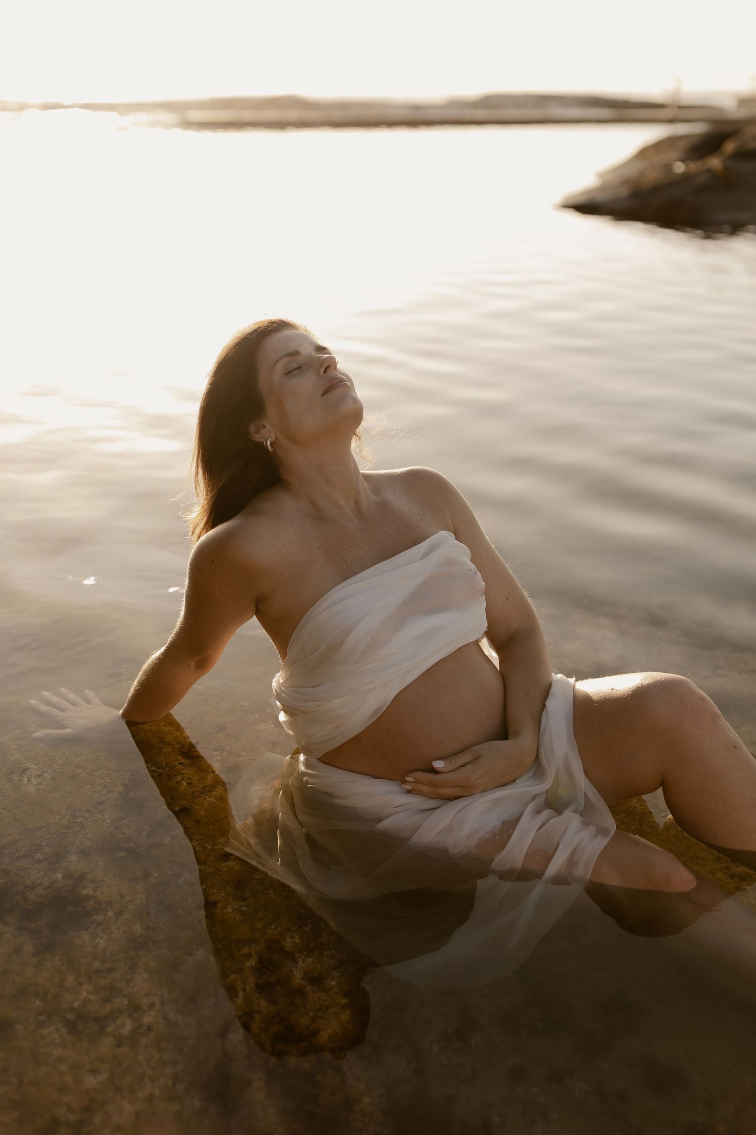Artistic sepia-toned photo series showing someone reclining on rocks by water during golden hour.