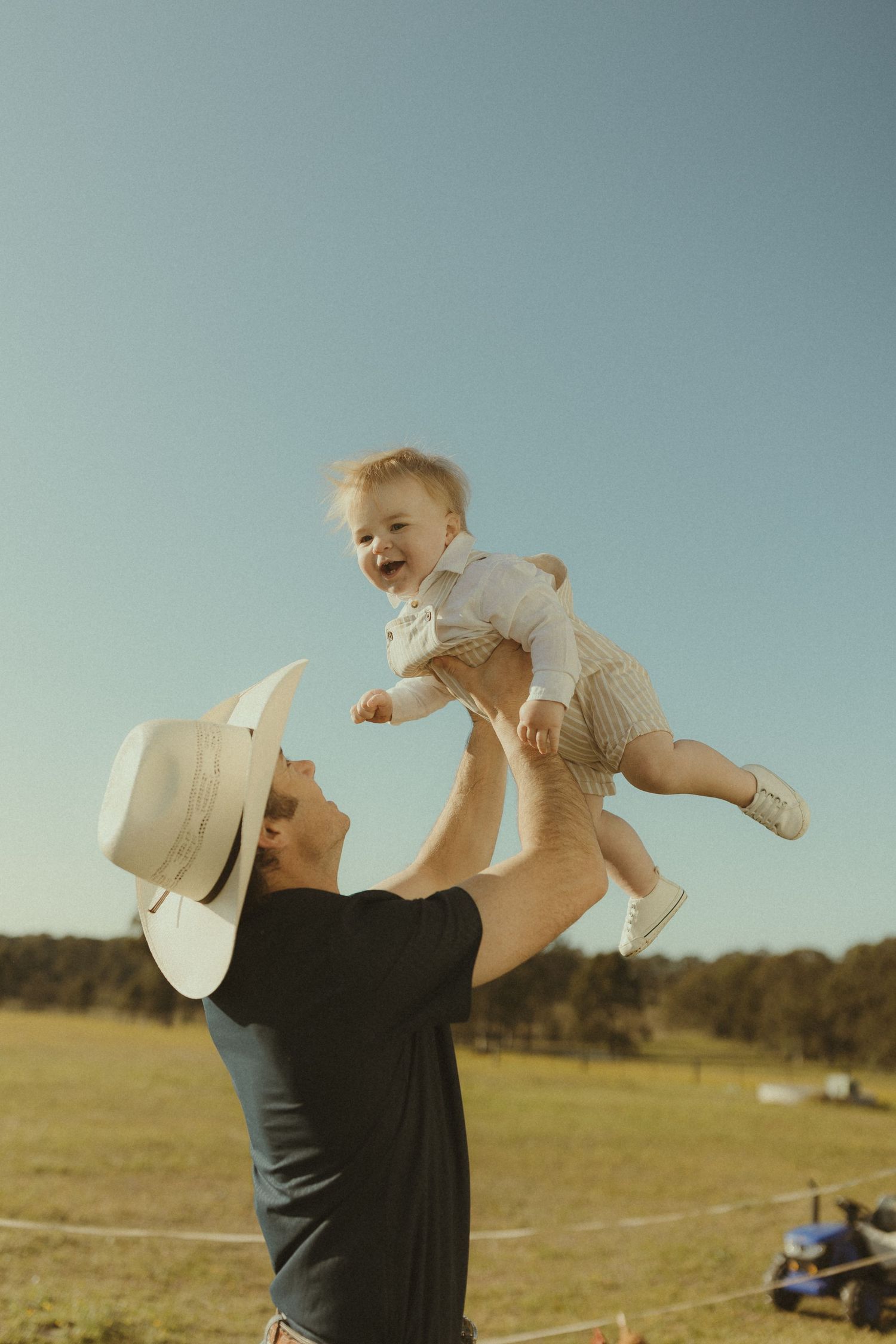 A joyful moment captured in a field as a child is playfully tossed in the air during golden hour.