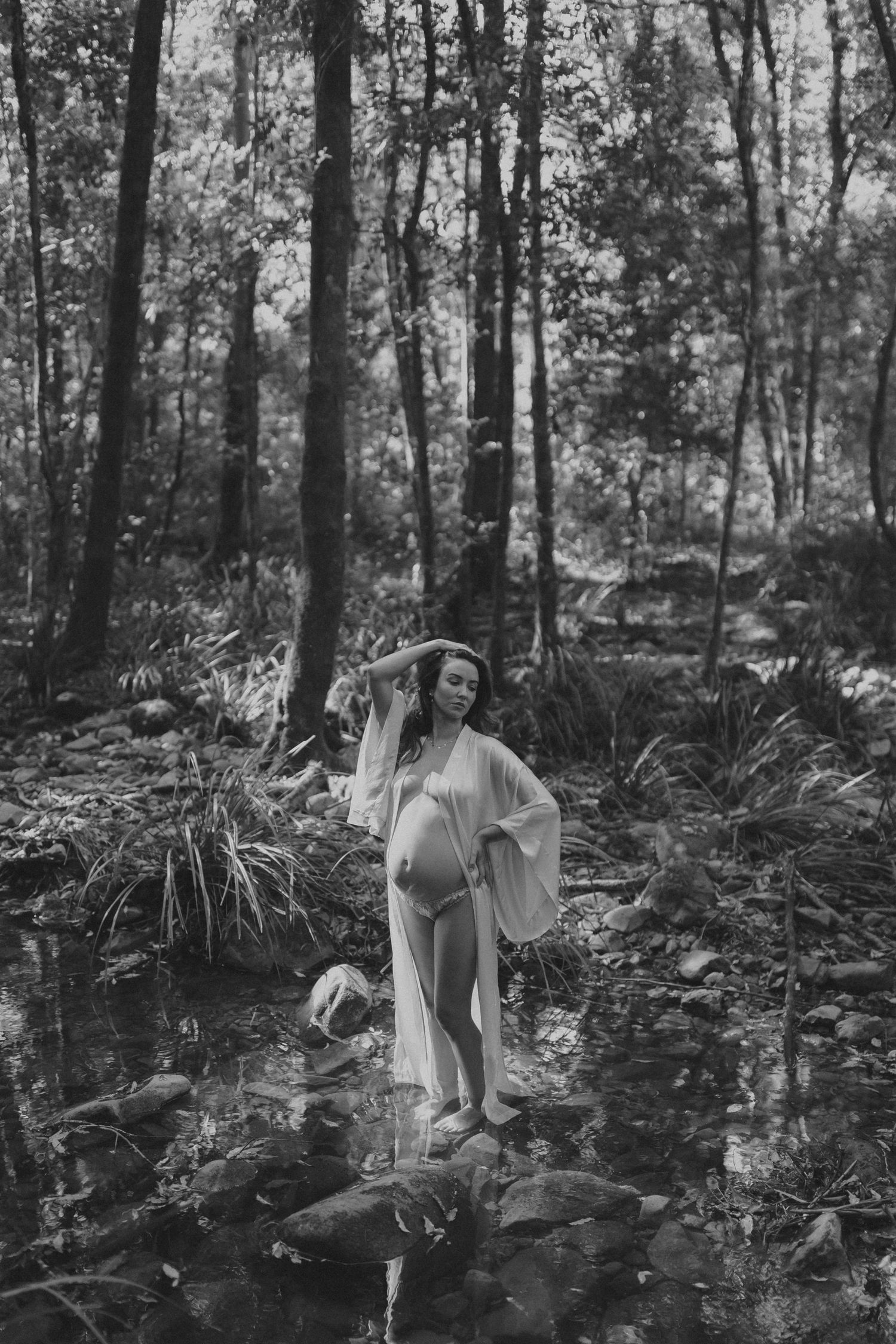 Black and white forest scene captures ethereal moments as a figure moves gracefully through misty woodland.